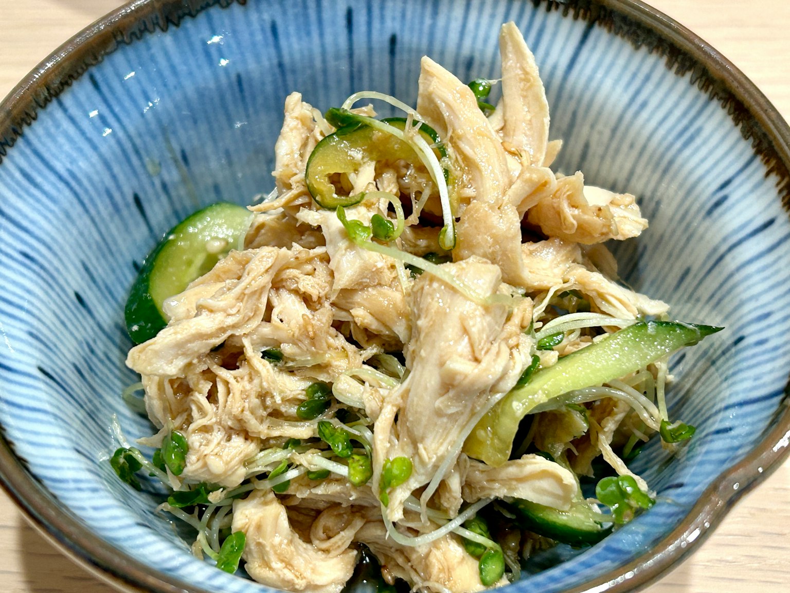 Insalata di pollo sfilacciato con cetrioli in una ciotola blu
