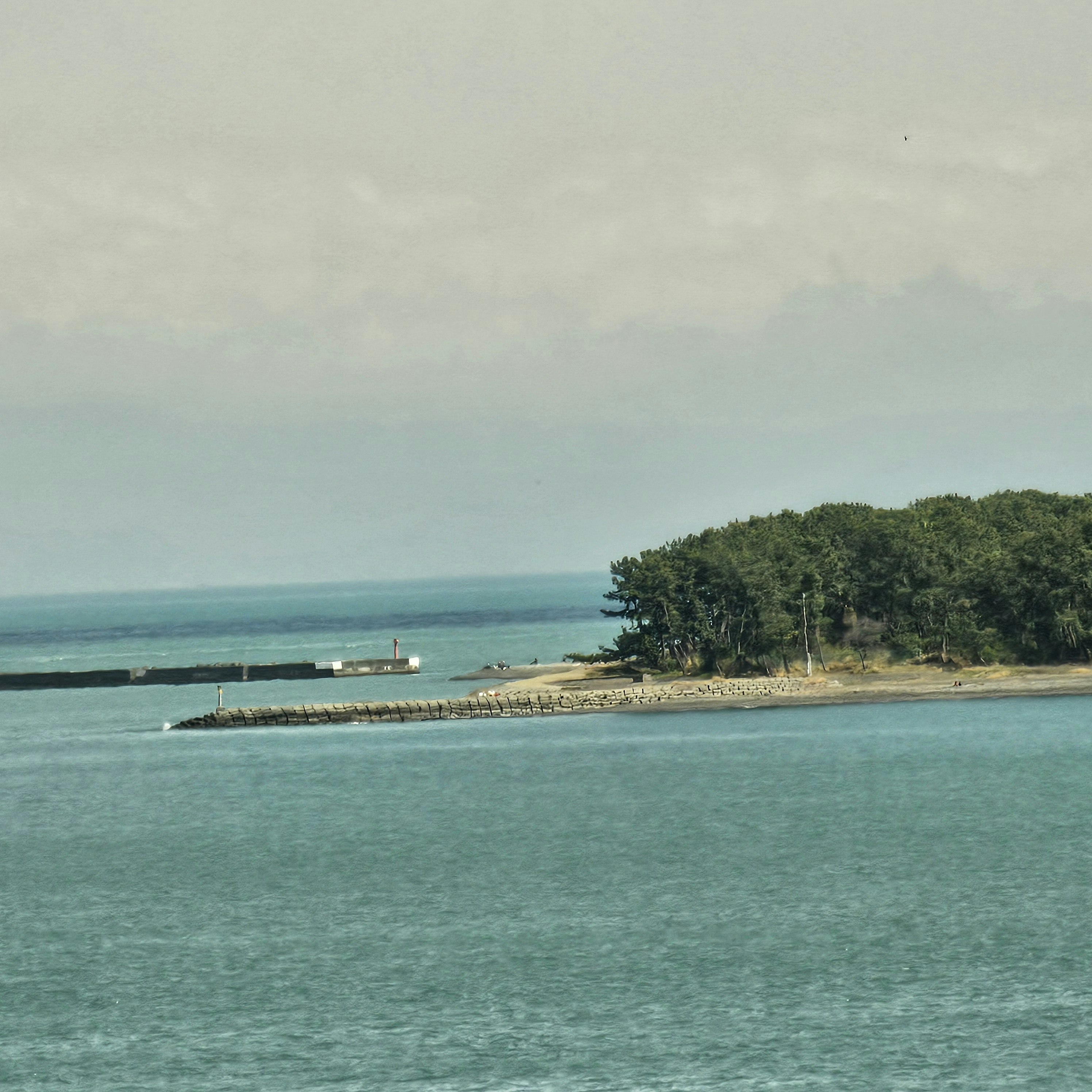 paesaggio costiero con diga frangiflutti e piccolo molo
