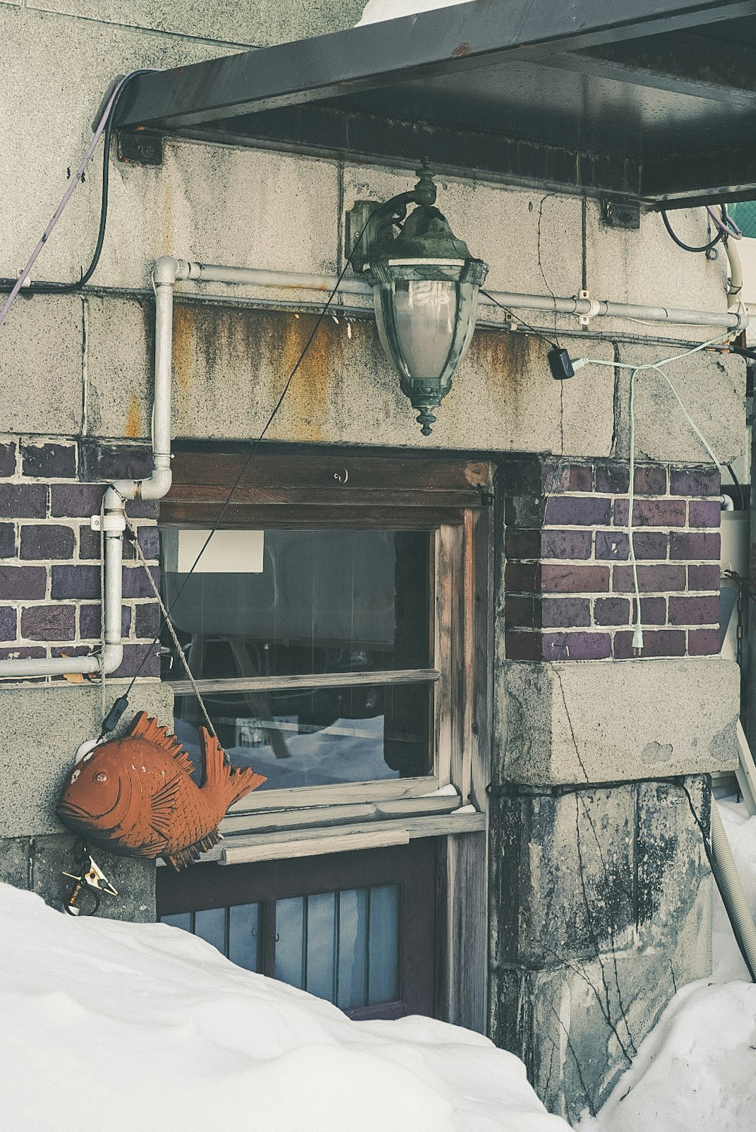 积雪的巷道墙面上旧式水泵与管道