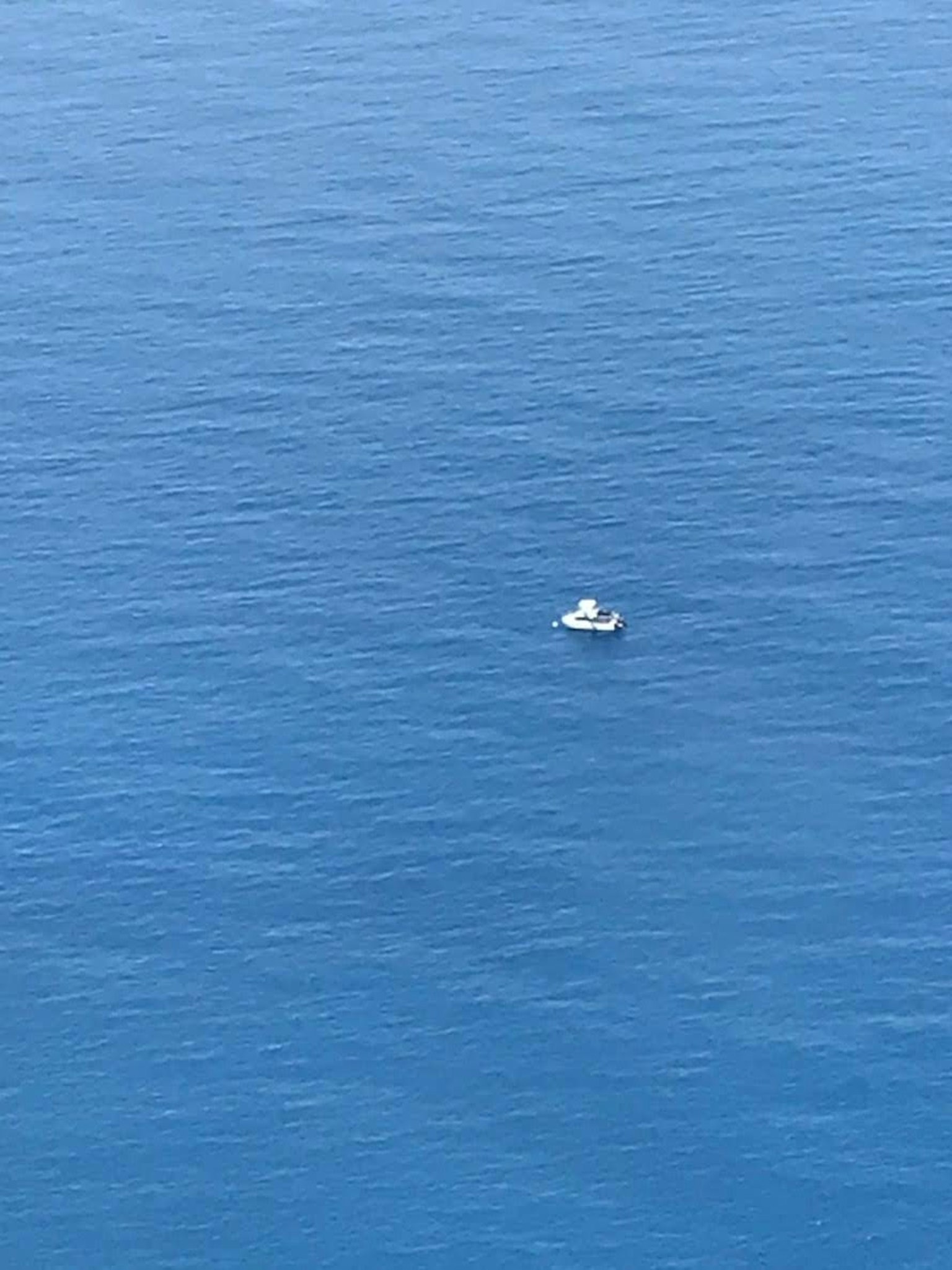 A small boat floating on a vast blue ocean