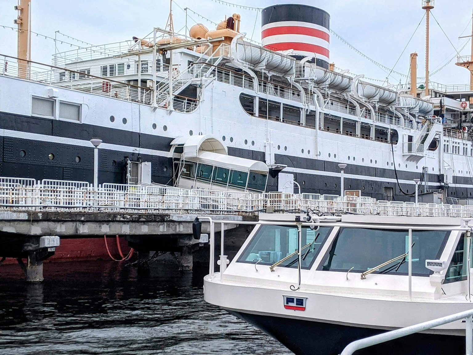 Gran barco de pasajeros atracado en el puerto con un pequeño bote cercano