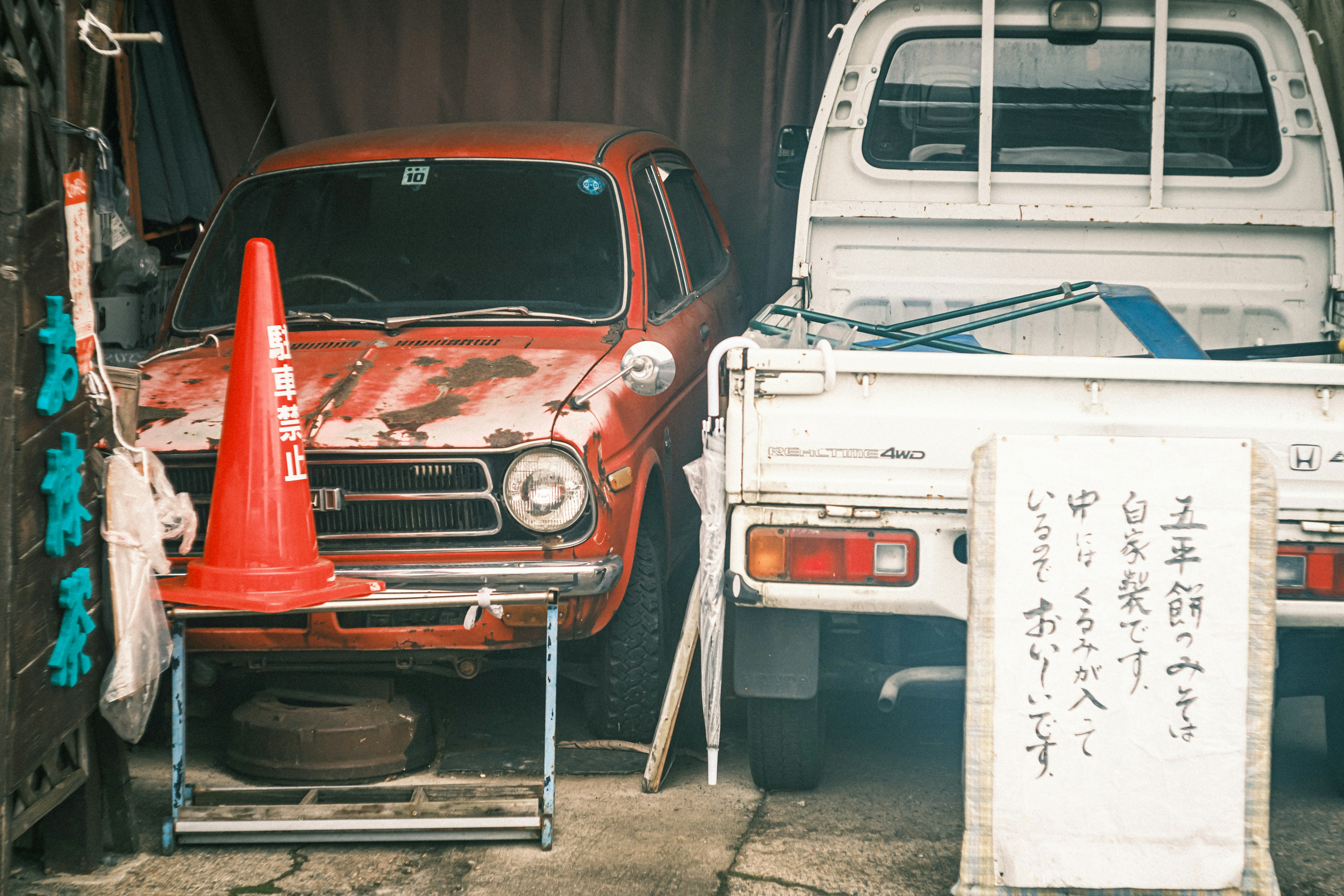 レトロな車と軽トラックが並ぶ整備スペースの前景
