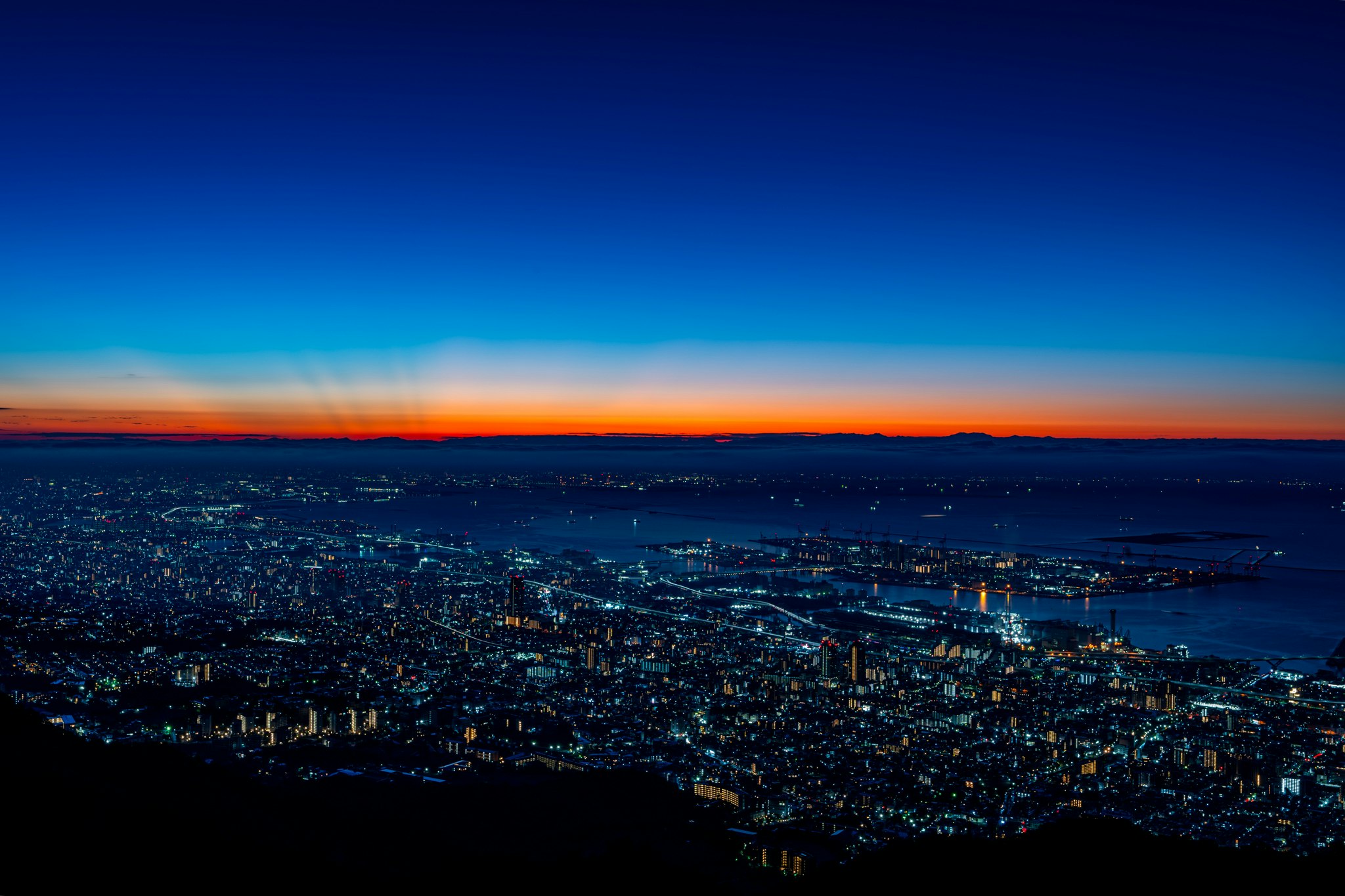夕焼けの空と海を望む夜景の大都市パノラマ