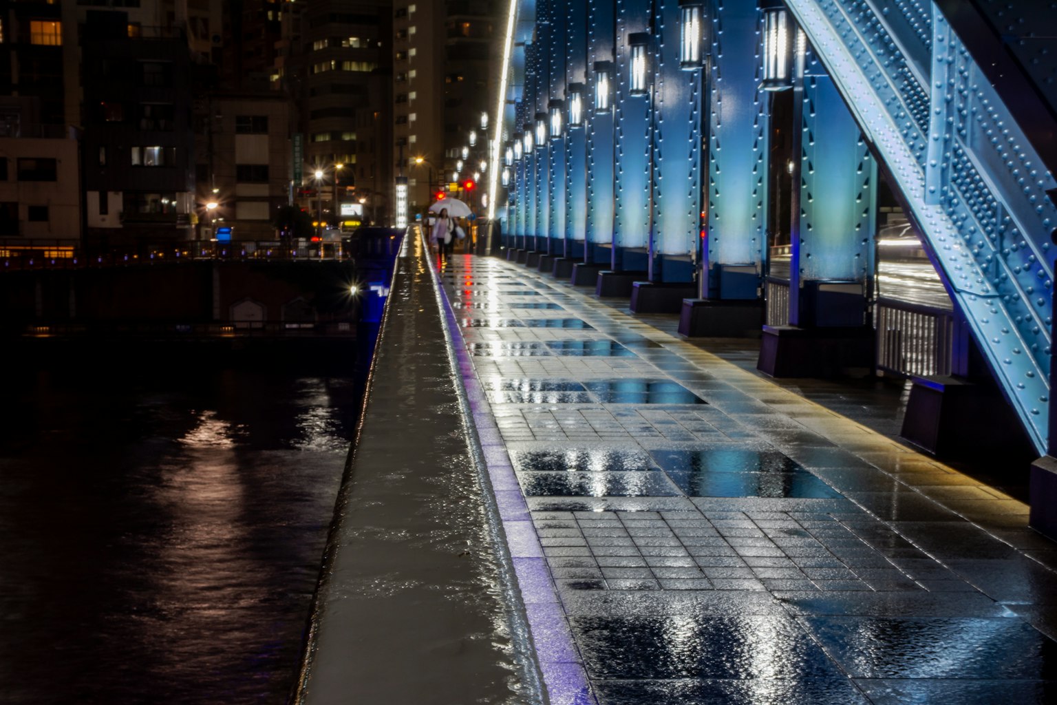 Vista notturna di un marciapiede di un ponte blu con riflessi sull'acqua