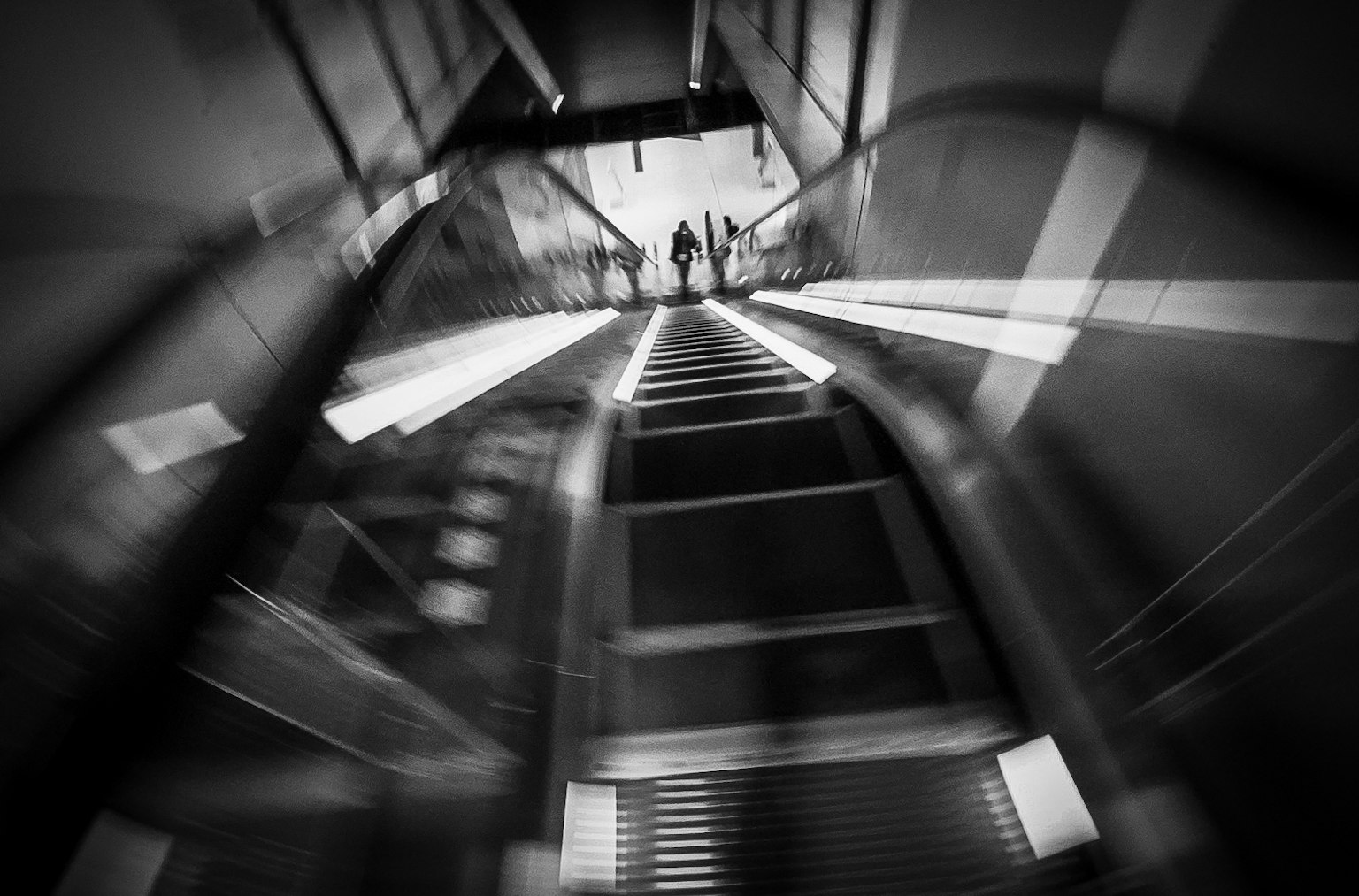 Black and white photo of people descending stairs with striking light trails