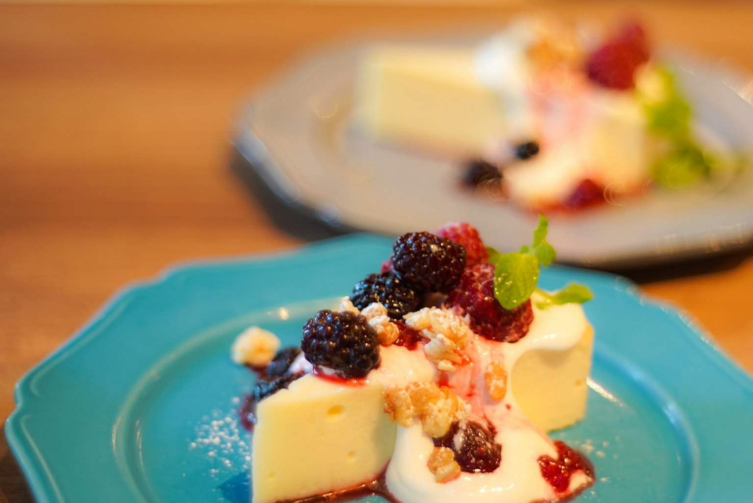 Cheesecake guarnito con frutti di bosco e menta su un piatto blu