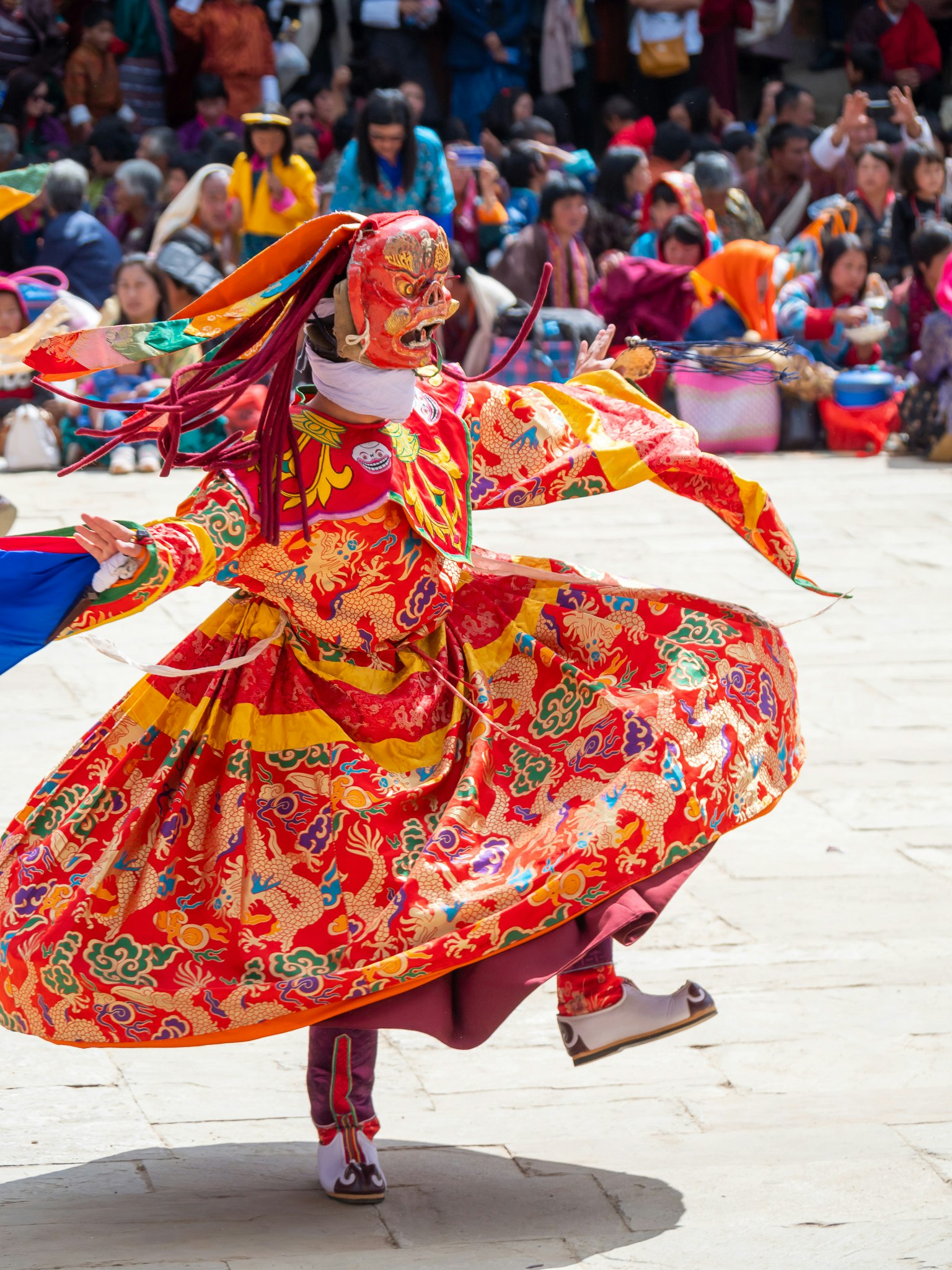 Una persona in un costume colorato che balla con uno sfondo vivace di spettatori