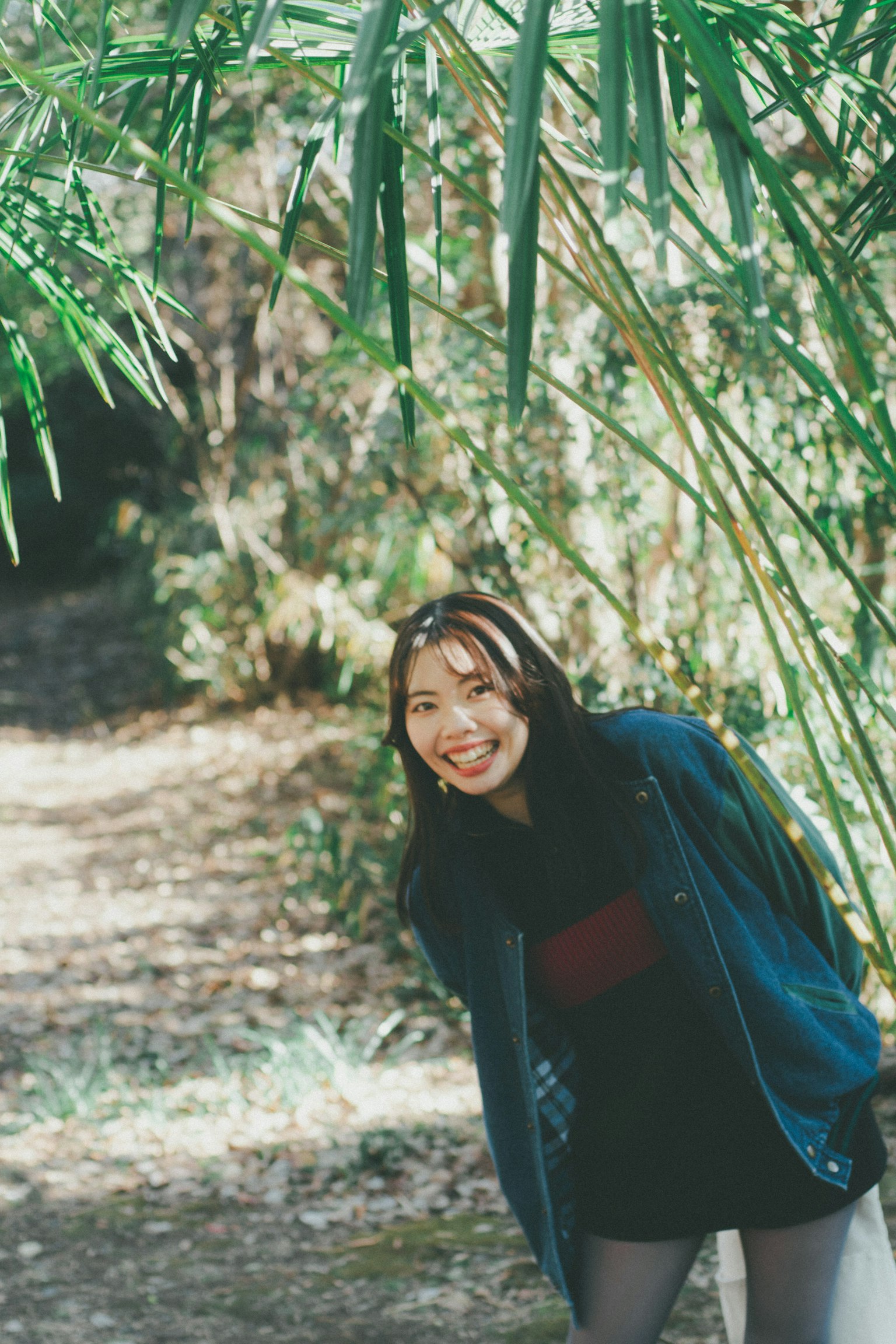 หญิงสาวยิ้มเล่นอยู่ท่ามกลางต้นไผ่สีเขียว