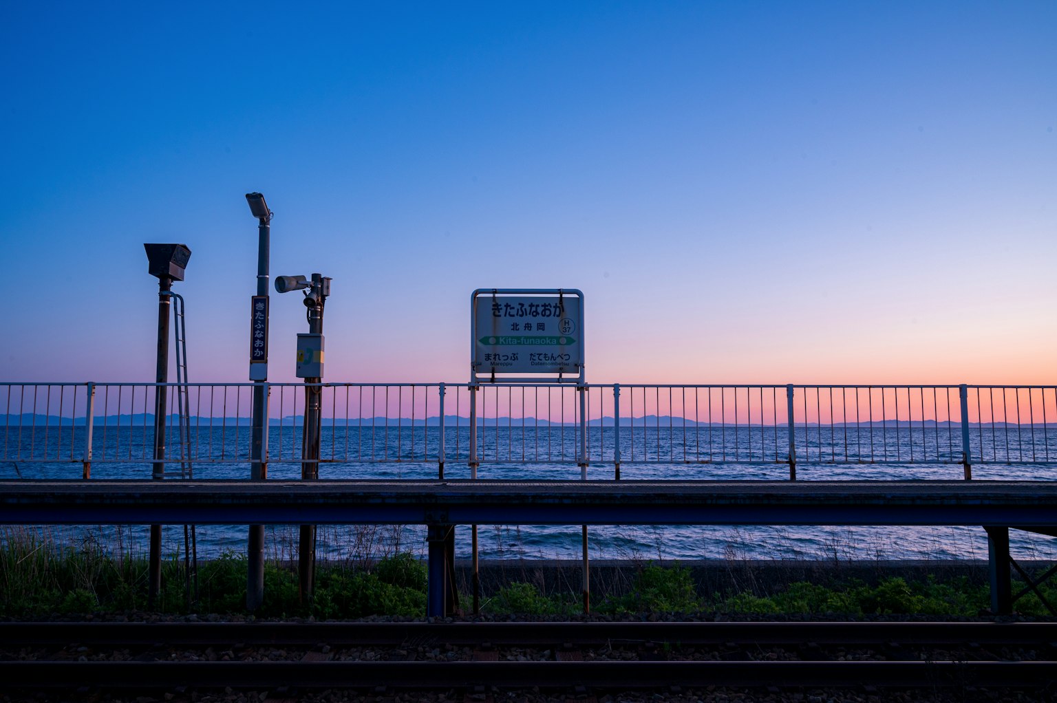 Vue de la gare ferroviaire avec océan en arrière-plan et coucher de soleil