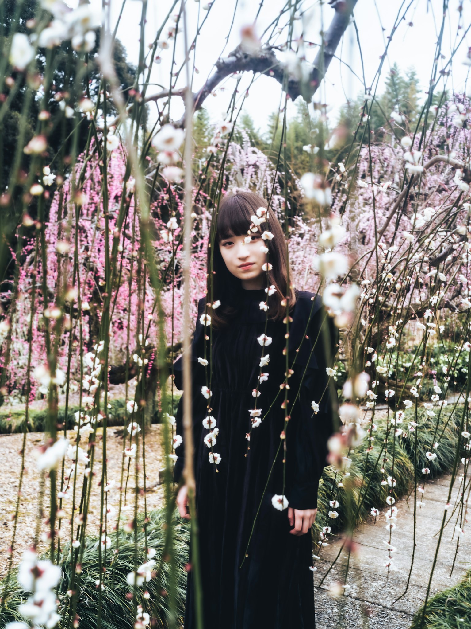 Une femme en robe noire se tenant dans un jardin en fleurs