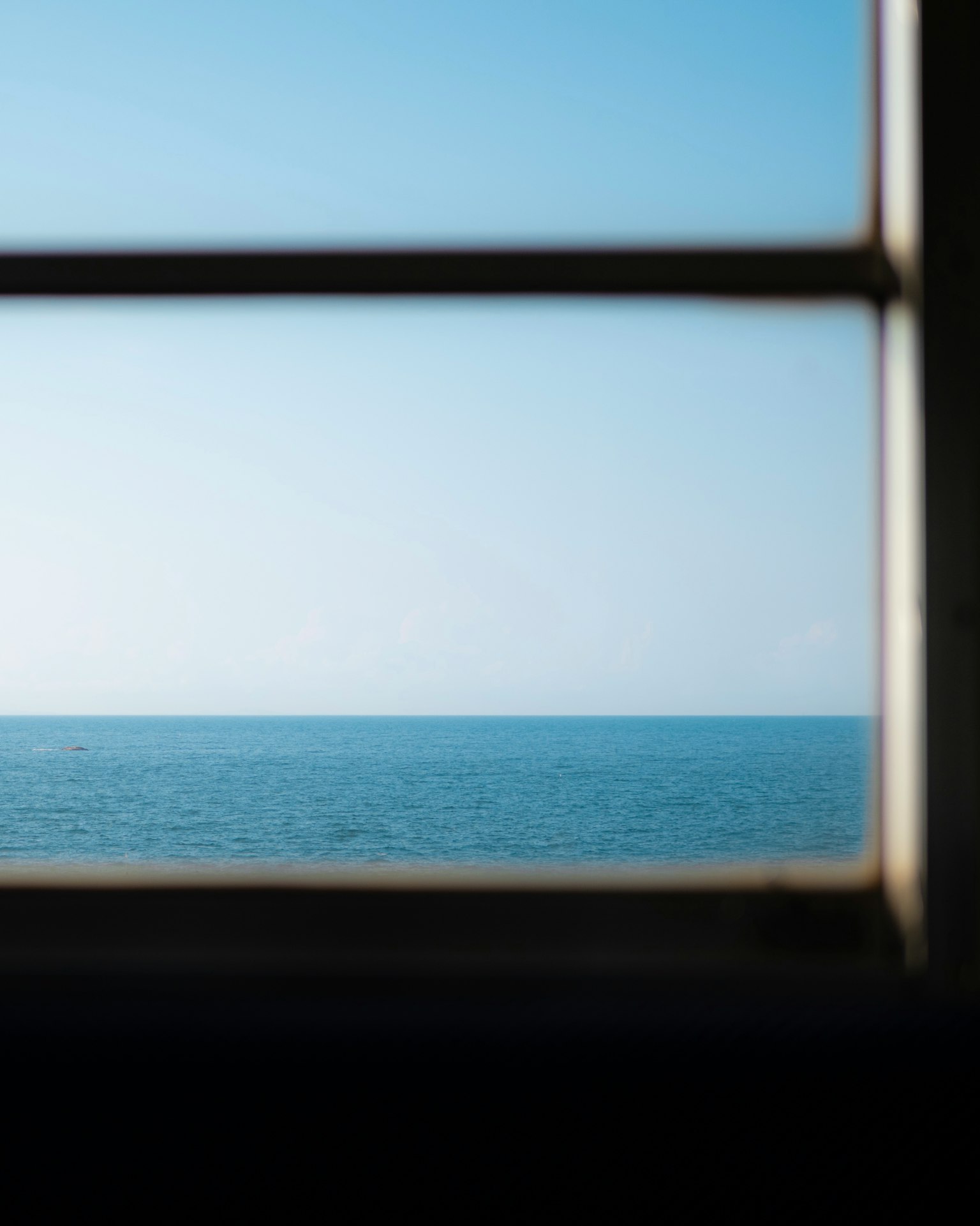 Pemandangan laut dan langit biru melalui jendela