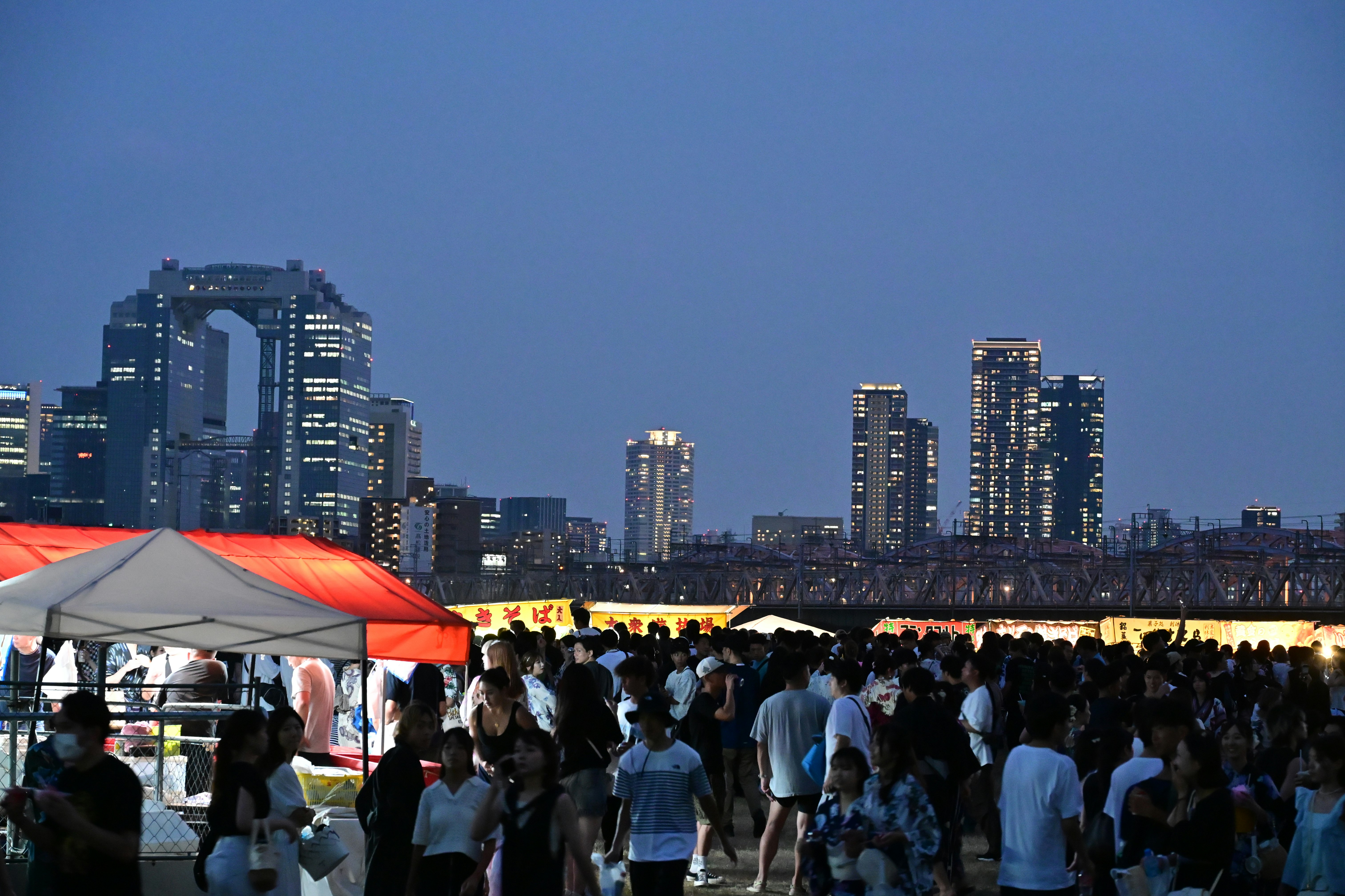 屋台の並ぶイベント会場と高層ビル群の夜景
