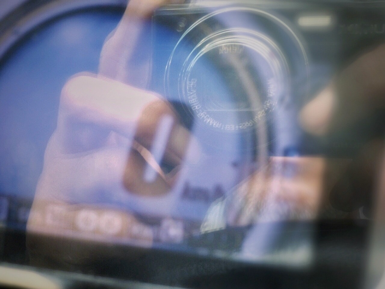 Bild, das die Reflexion einer Hand durch ein Kameraobjektiv zeigt