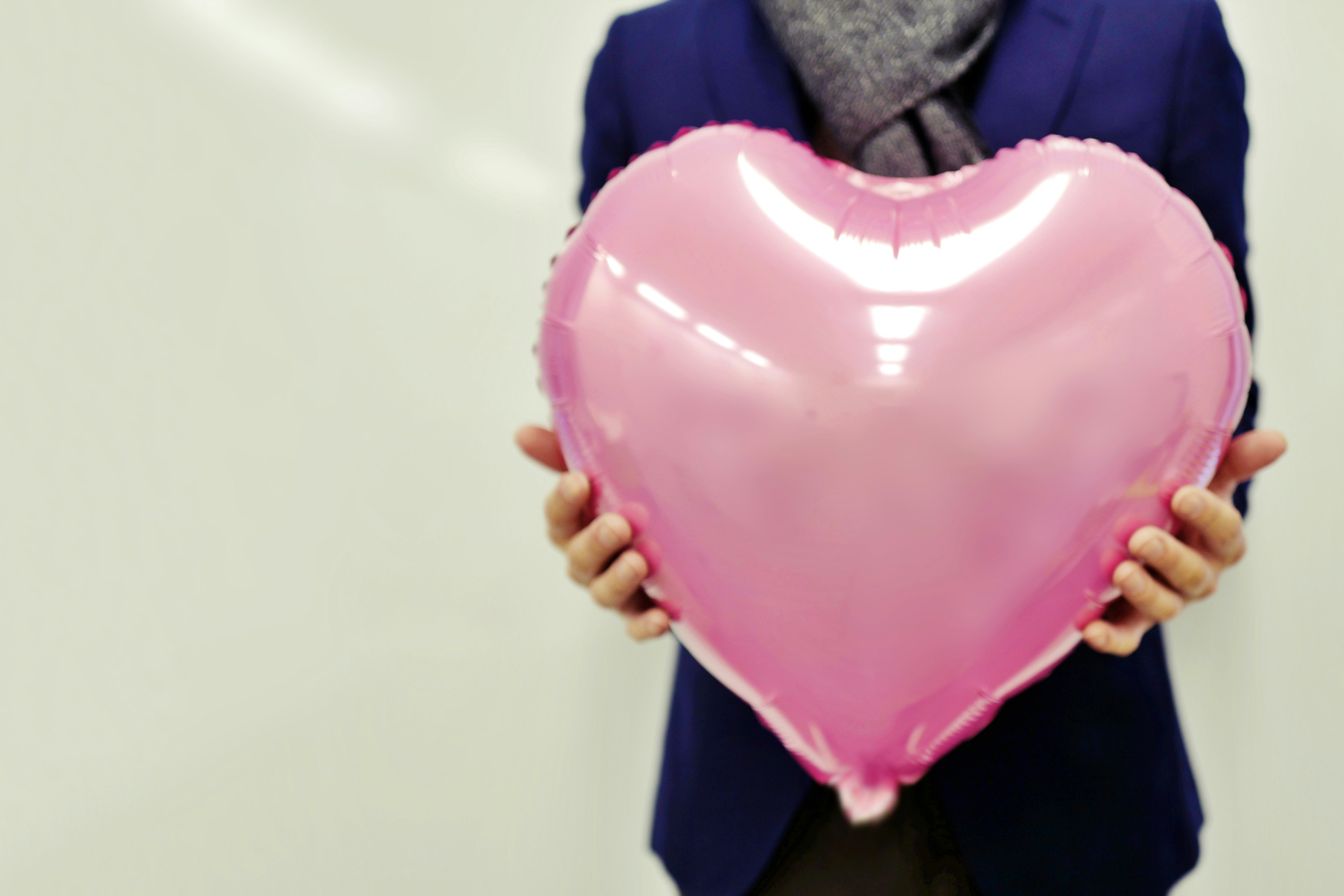hands holding a pink heart balloon