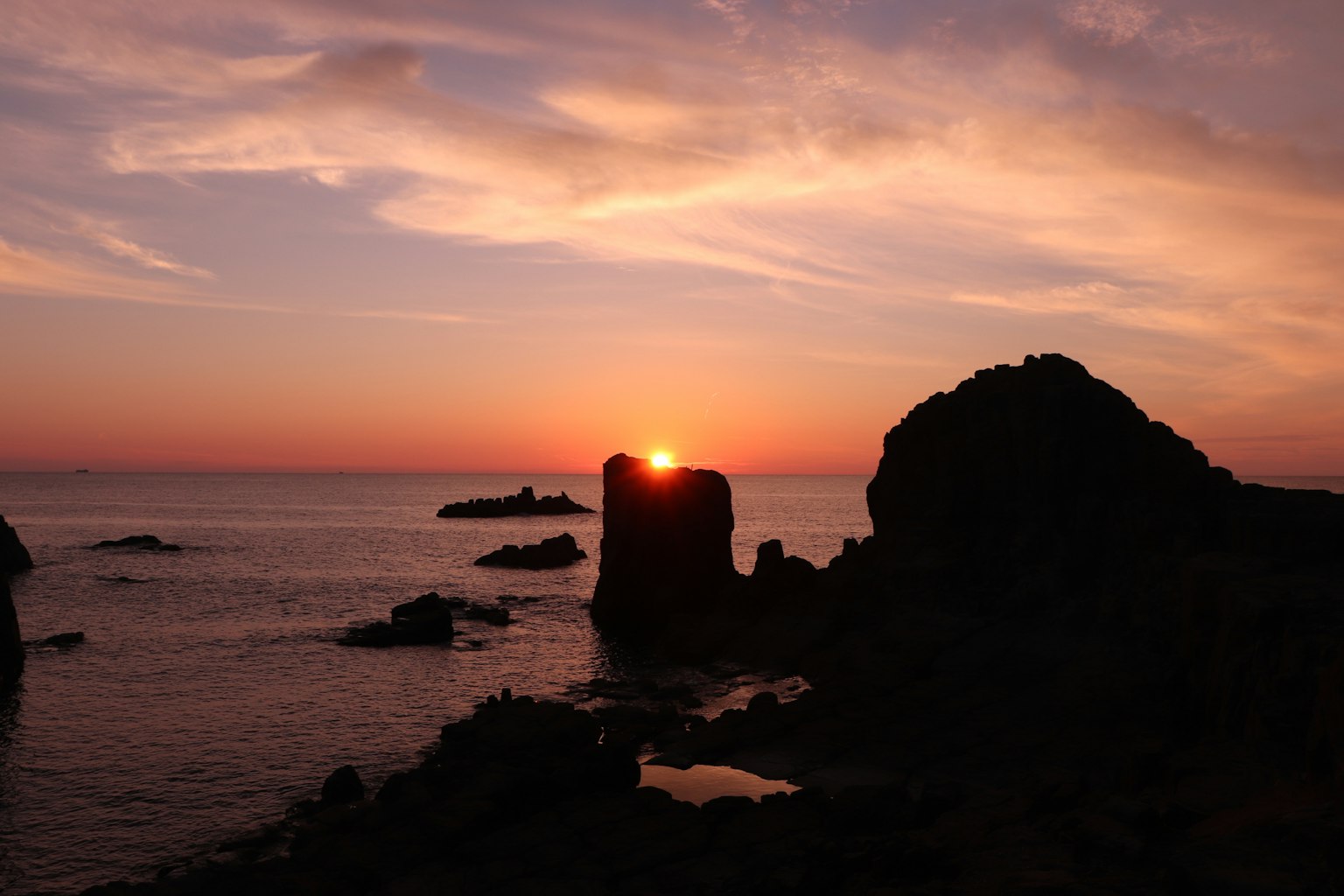 Coucher de soleil sur l'océan avec des silhouettes de formations rocheuses