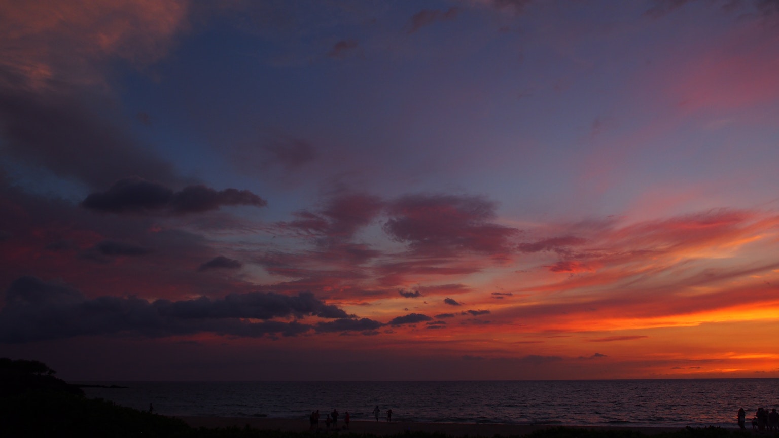 Atardecer vibrante sobre el océano con nubes coloridas y cielo naranja