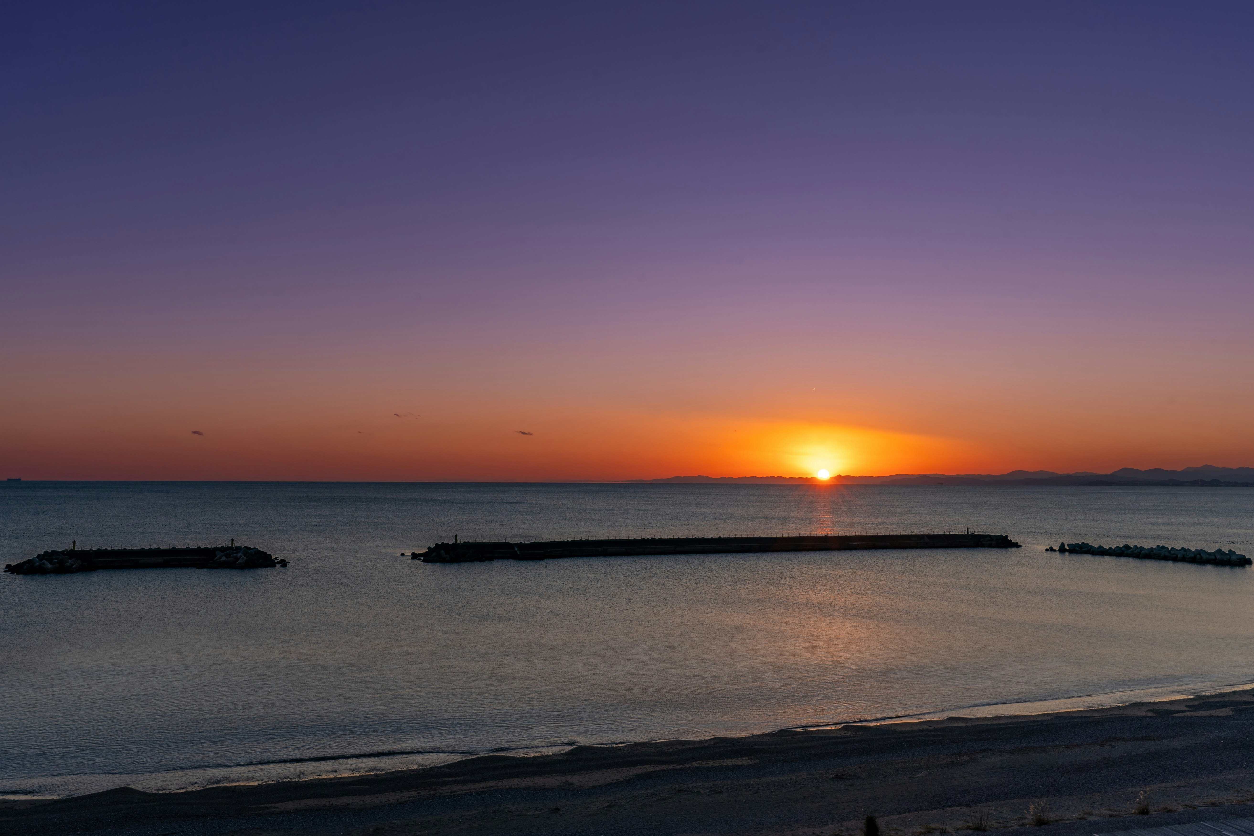 Coucher de soleil sur la mer avec des digues et un horizon lumineux