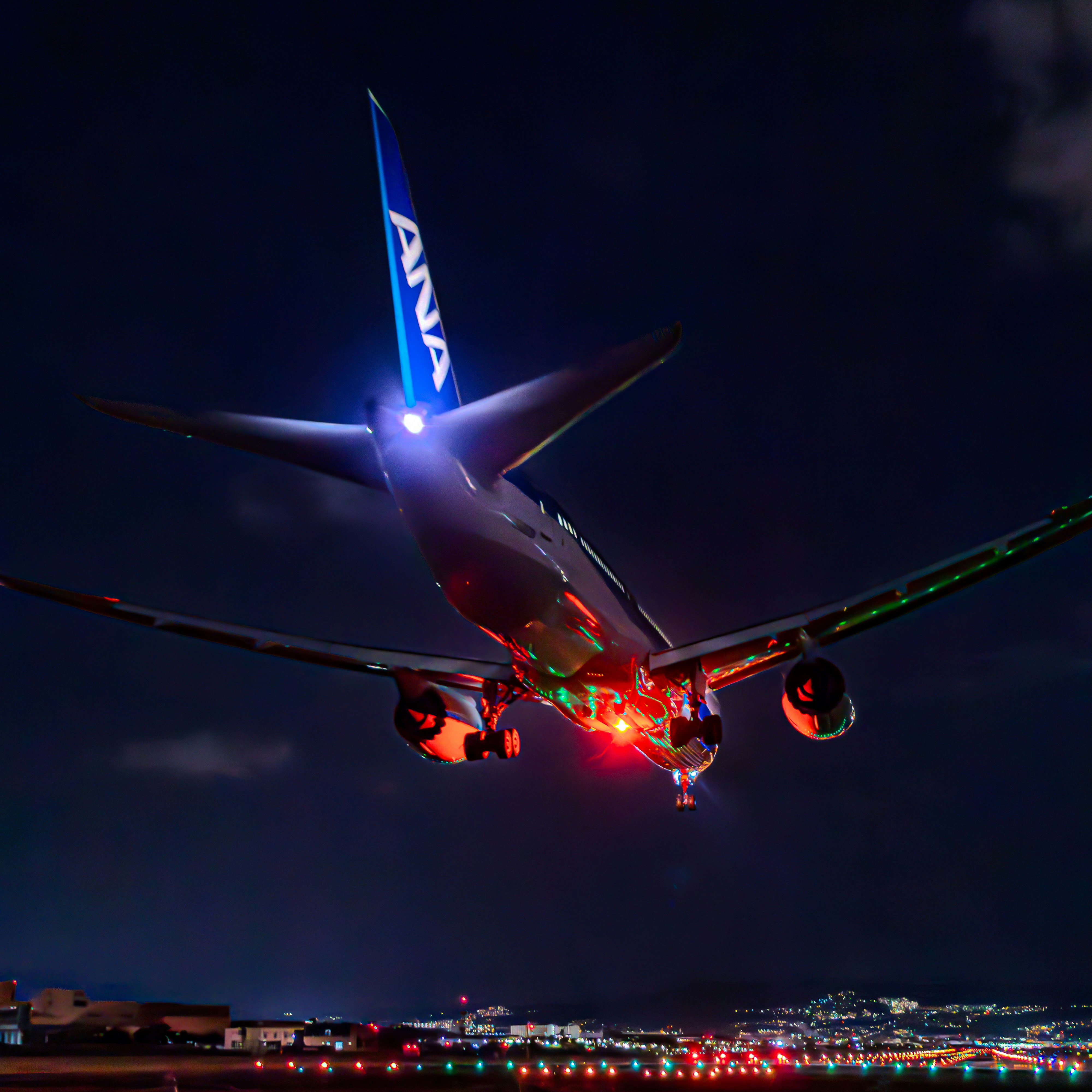 夜の伊丹空港で離陸するANA機の機体と滑走路の灯り