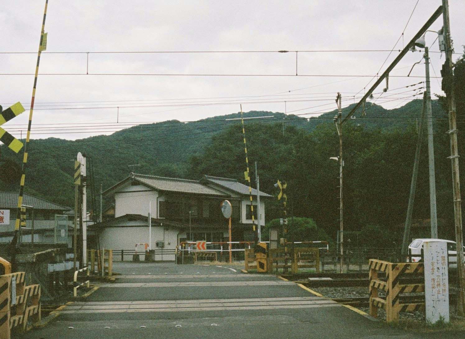 有铁路道口的郊区道路、电线杆与远处丘陵景观图片