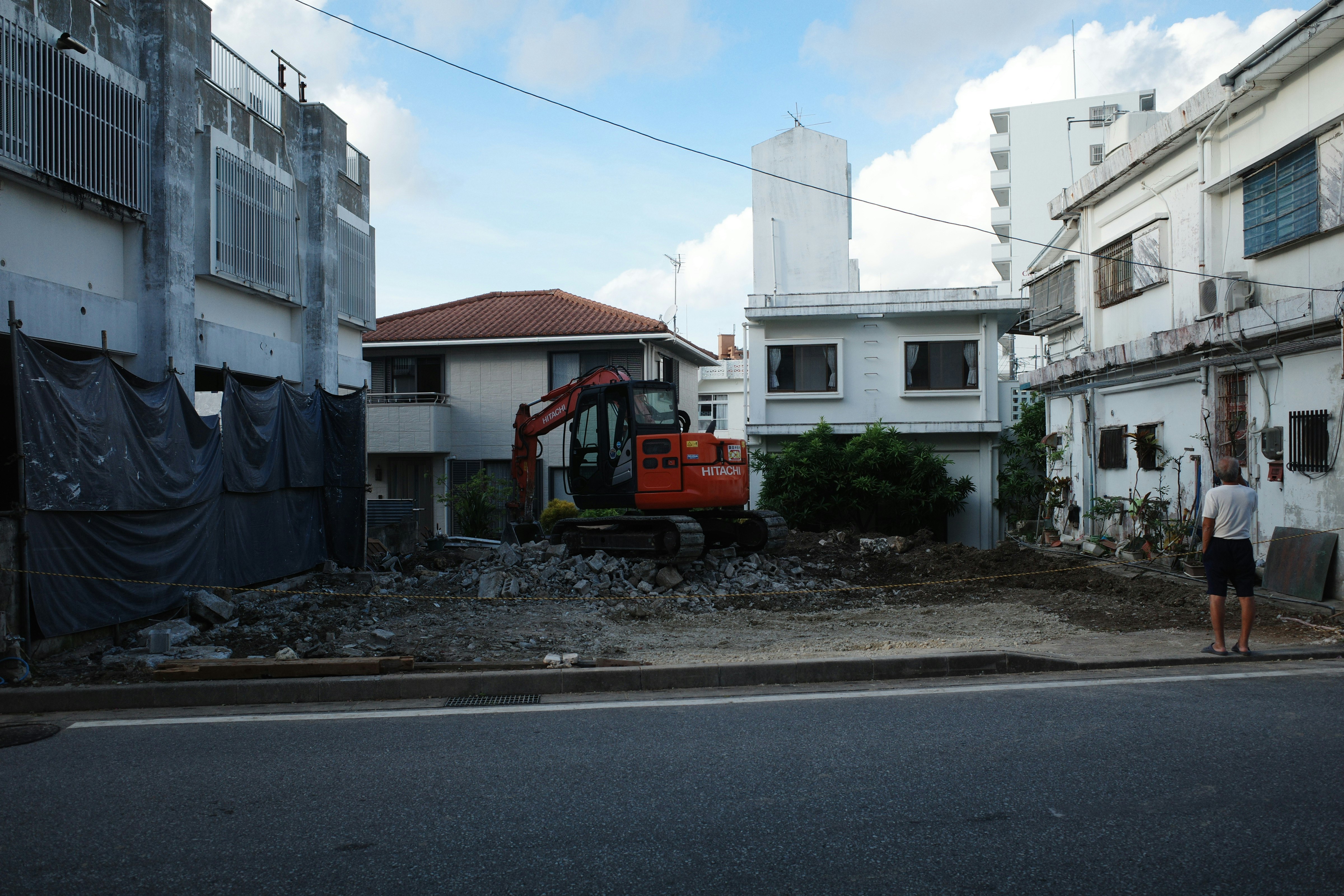 路地の瓦礫と建設機械がある沖縄の街並み