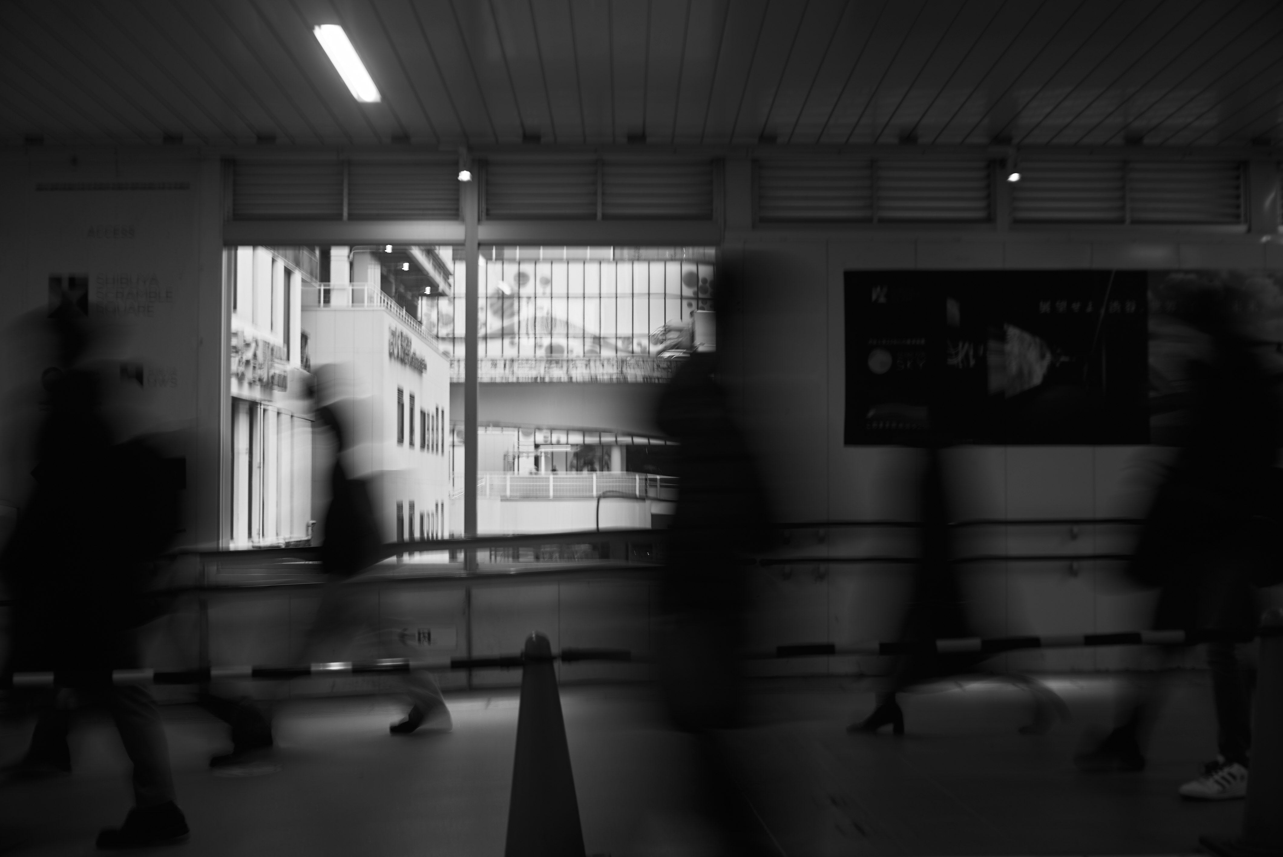 dim indoor hallway with benches and blurred silhouettes
