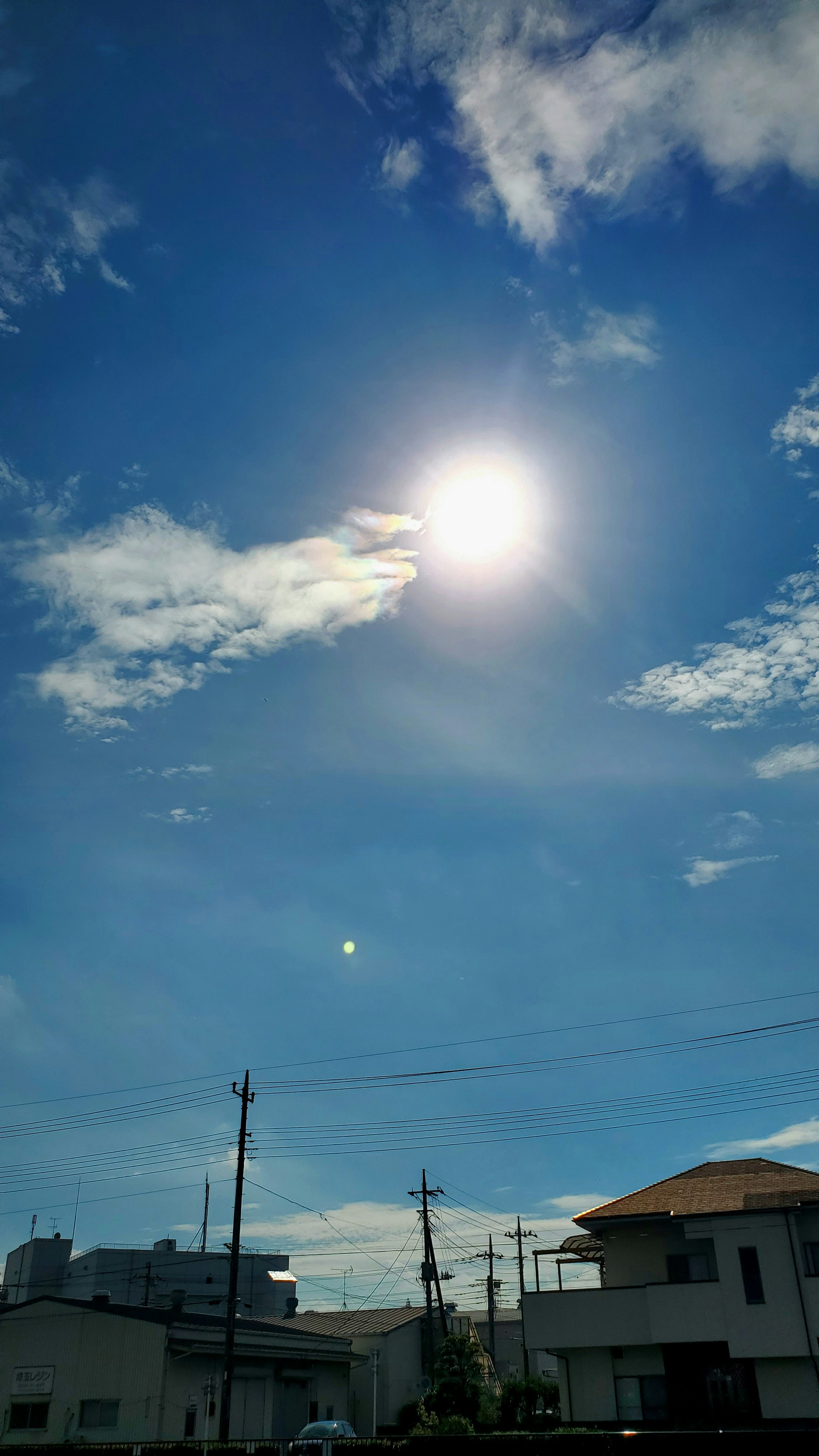 青空に浮かぶ雲と夕日が差し込む住宅街の空