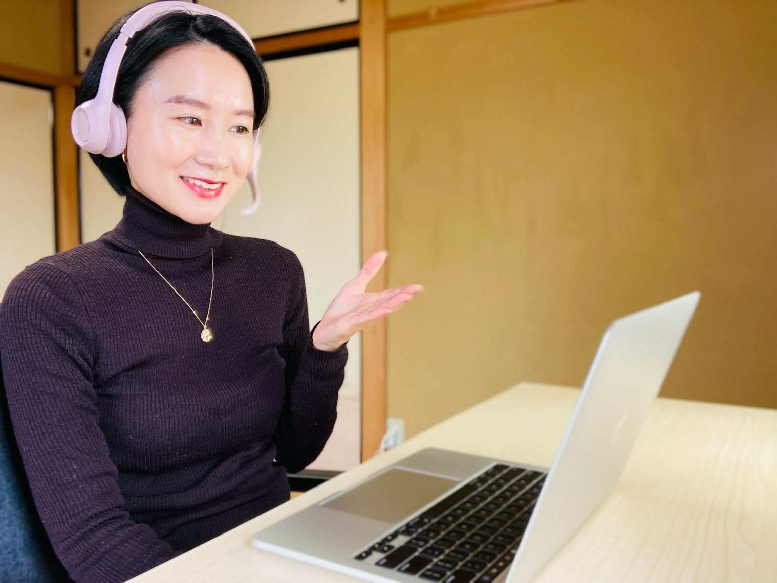 Seorang wanita mengenakan headset berbicara di depan laptop
