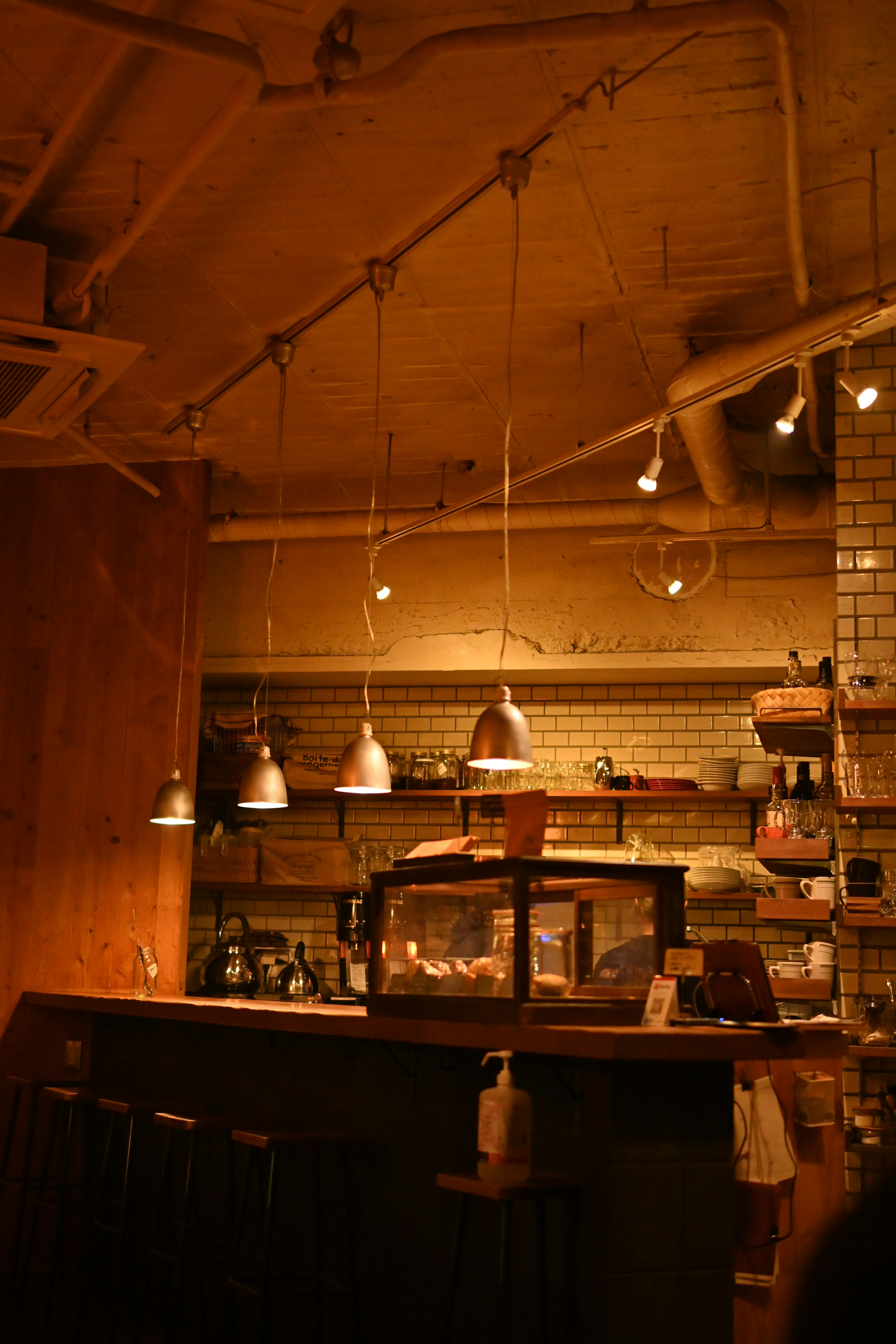 レンガ壁のカフェ厨房で並ぶ照明とカウンターのある店内