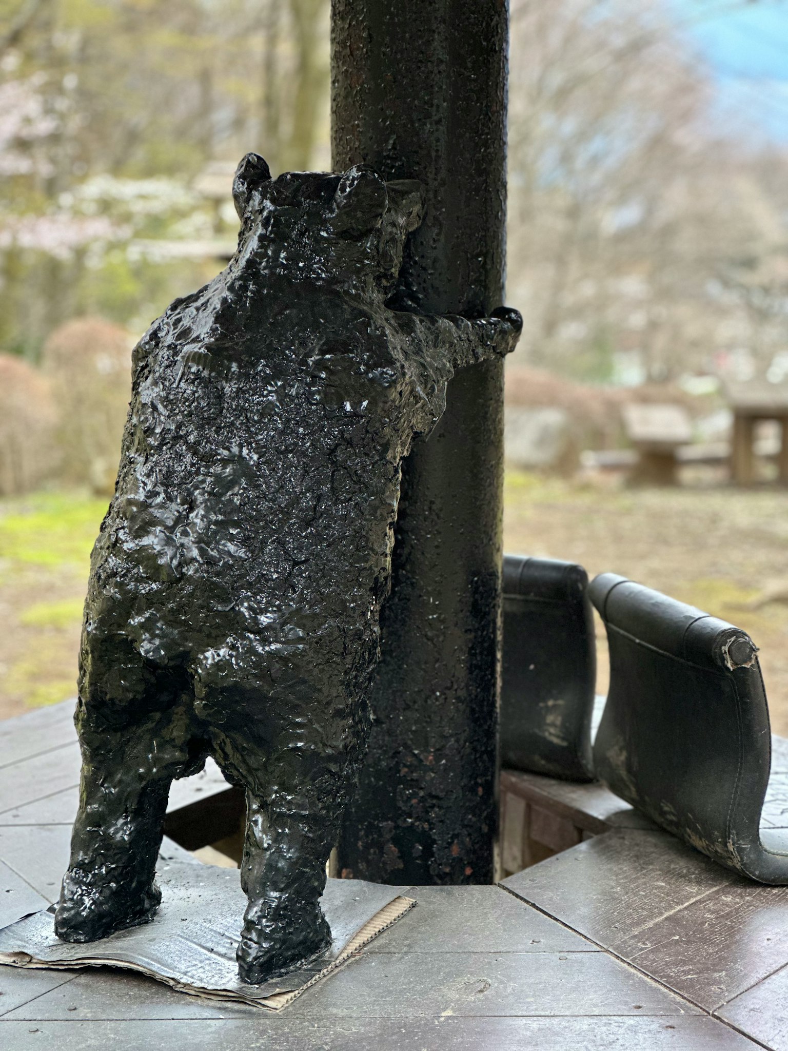Una scultura di orso nero che si appoggia a un pilastro in un ambiente esterno pittoresco