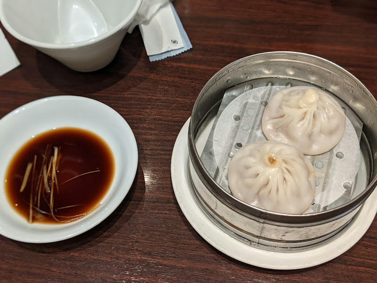 蒸饺在蒸笼里，旁边有酱油和生姜