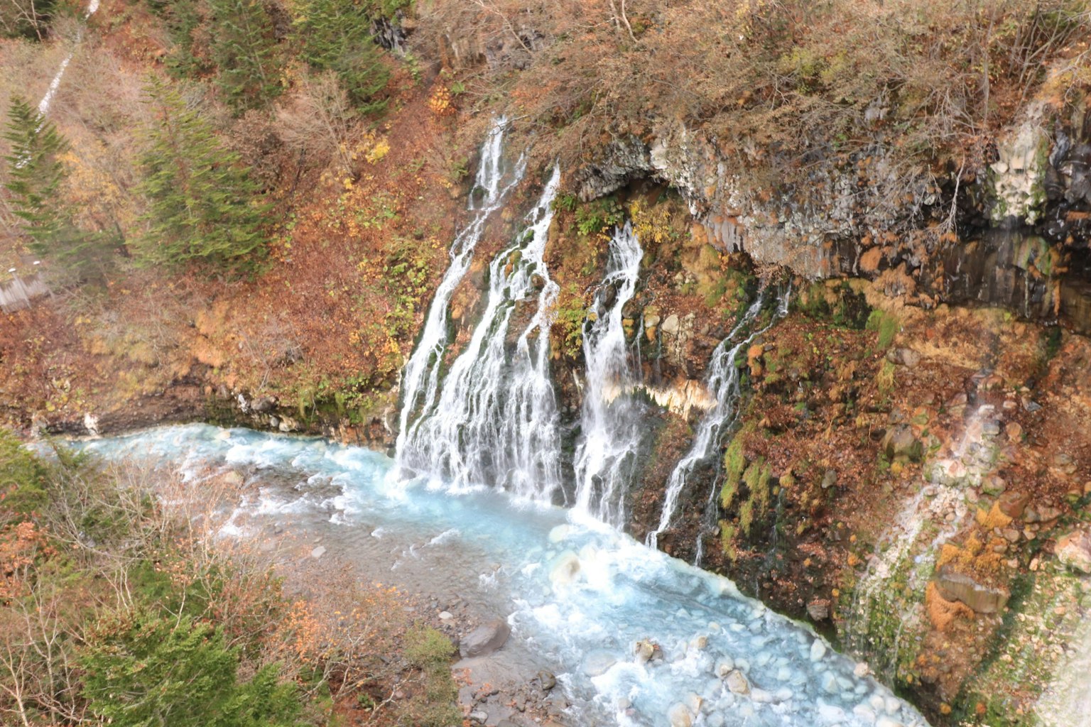 Una bella cascata che scorre in un ambiente naturale con colori armoniosi e foglie autunnali