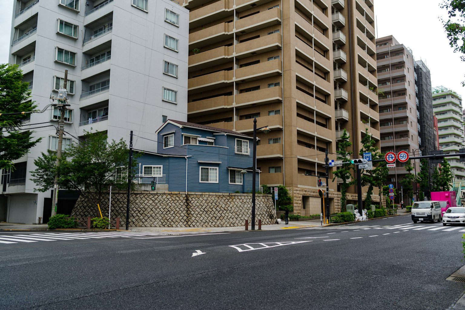 A small blue house next to tall buildings in an urban setting