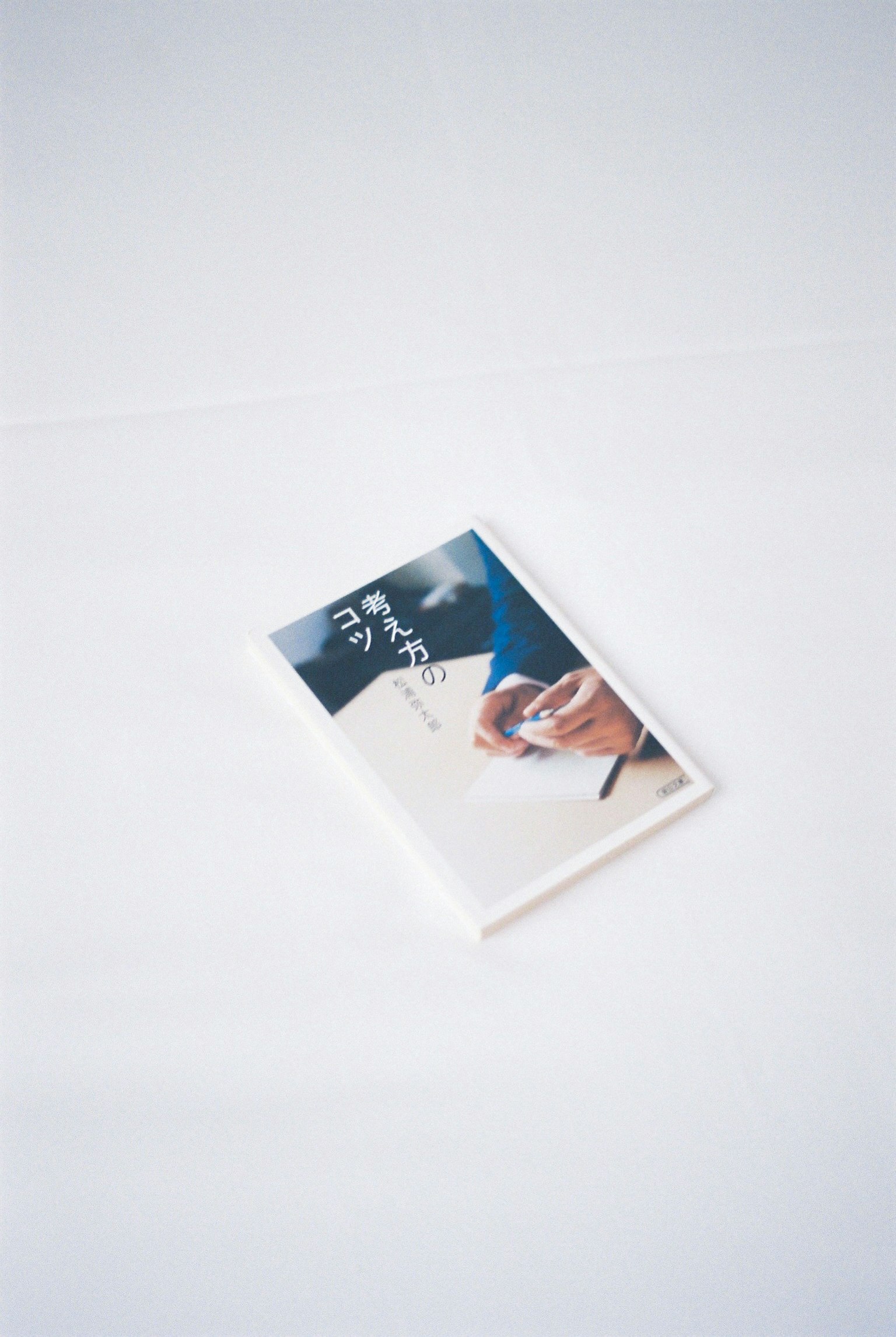 หนังสือเล่มเล็กวางอยู่บนพื้นหลังสีขาวที่ถูกถืออยู่ในมือ