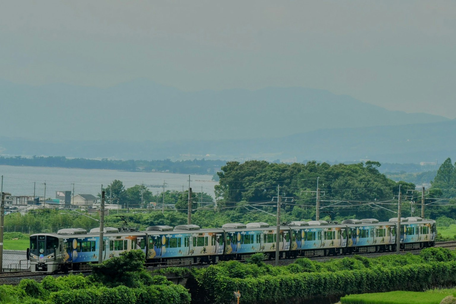 รถไฟวิ่งผ่านภูมิทัศน์เขียวชอุ่มพร้อมภูเขาในพื้นหลัง