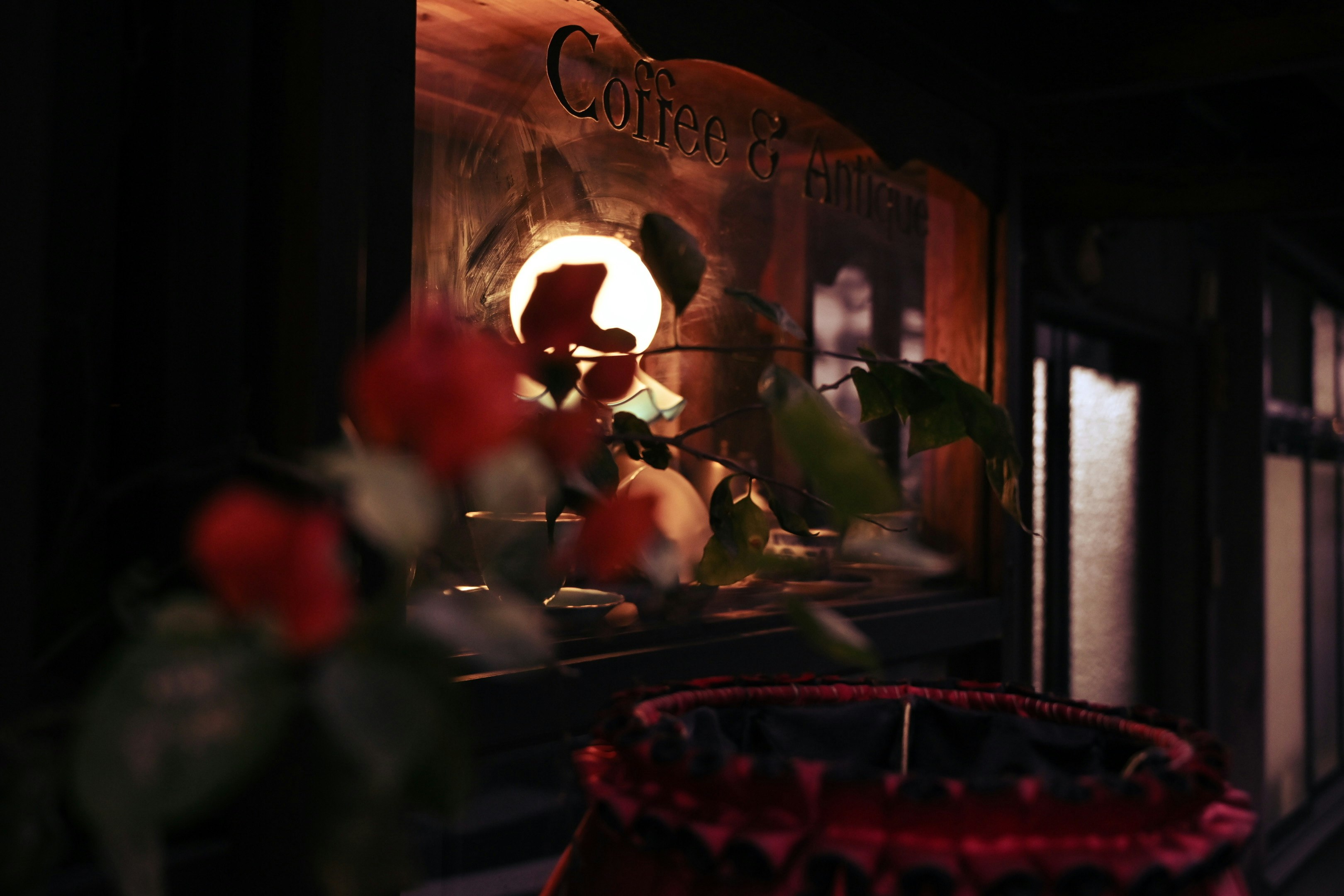 fleurs de roses et enseigne de café vues à travers une vitre