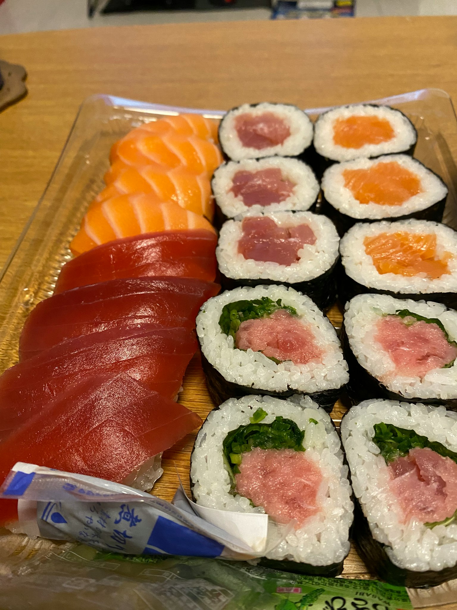 Fresh sushi platter featuring salmon and tuna sashimi with assorted maki rolls