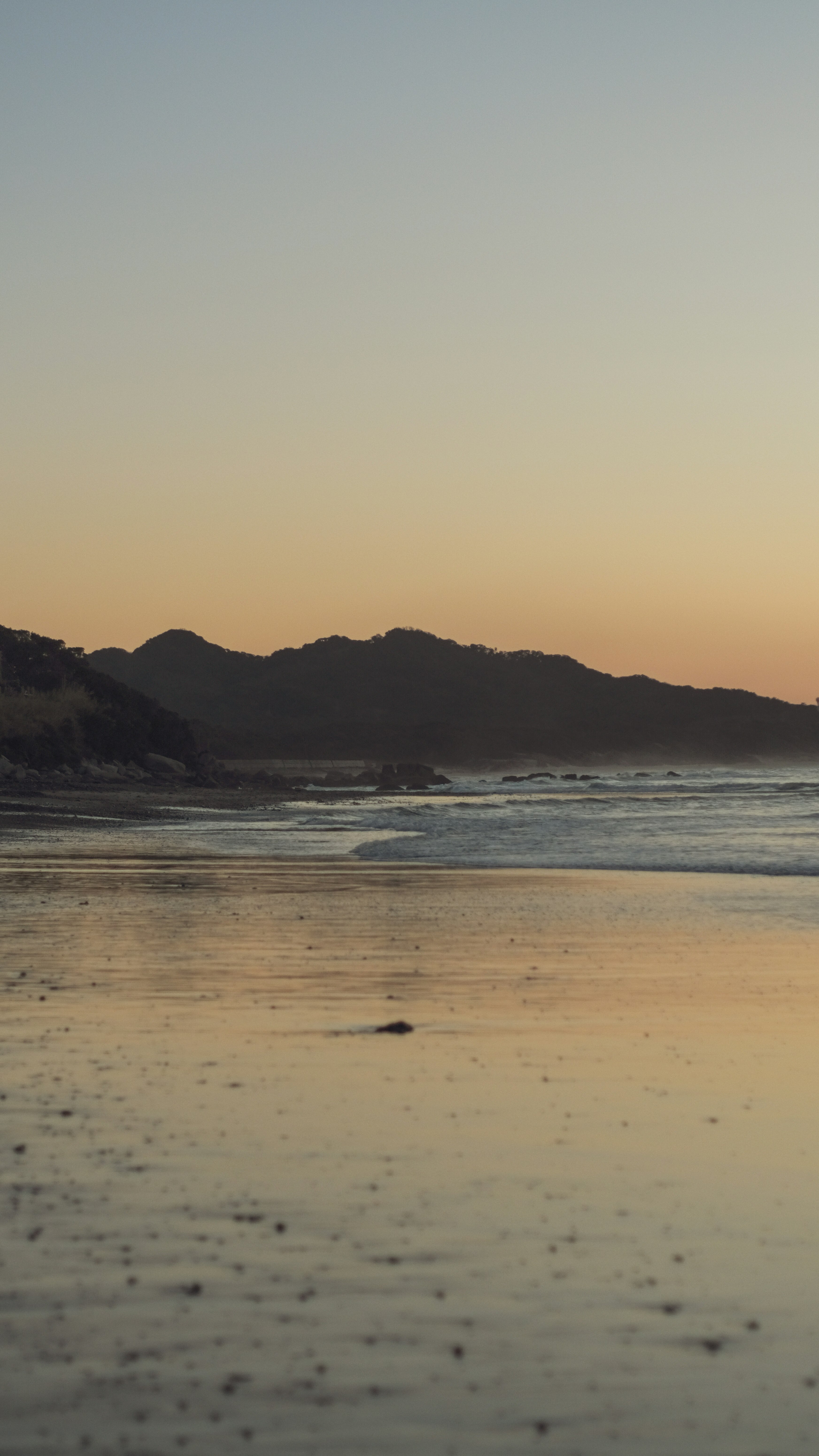夕暮れの砂浜と遠くの山並みが広がる海岸の風景