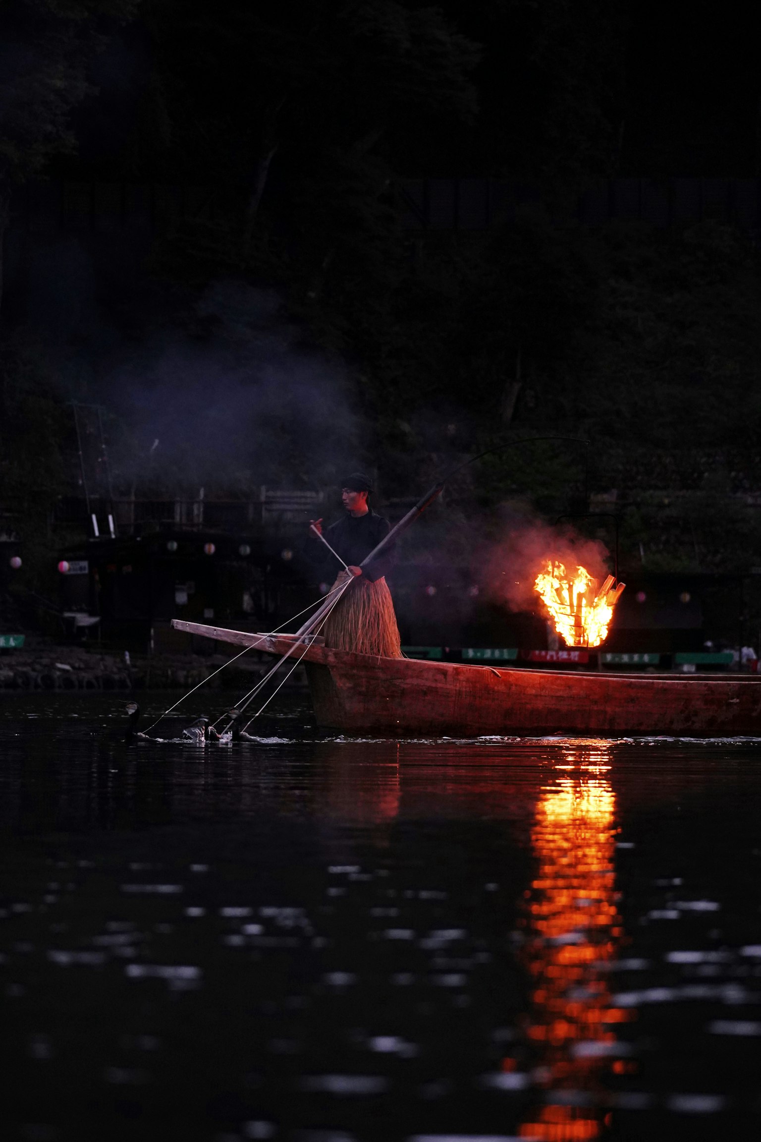 Perahu kecil di atas air gelap dengan api yang menyala