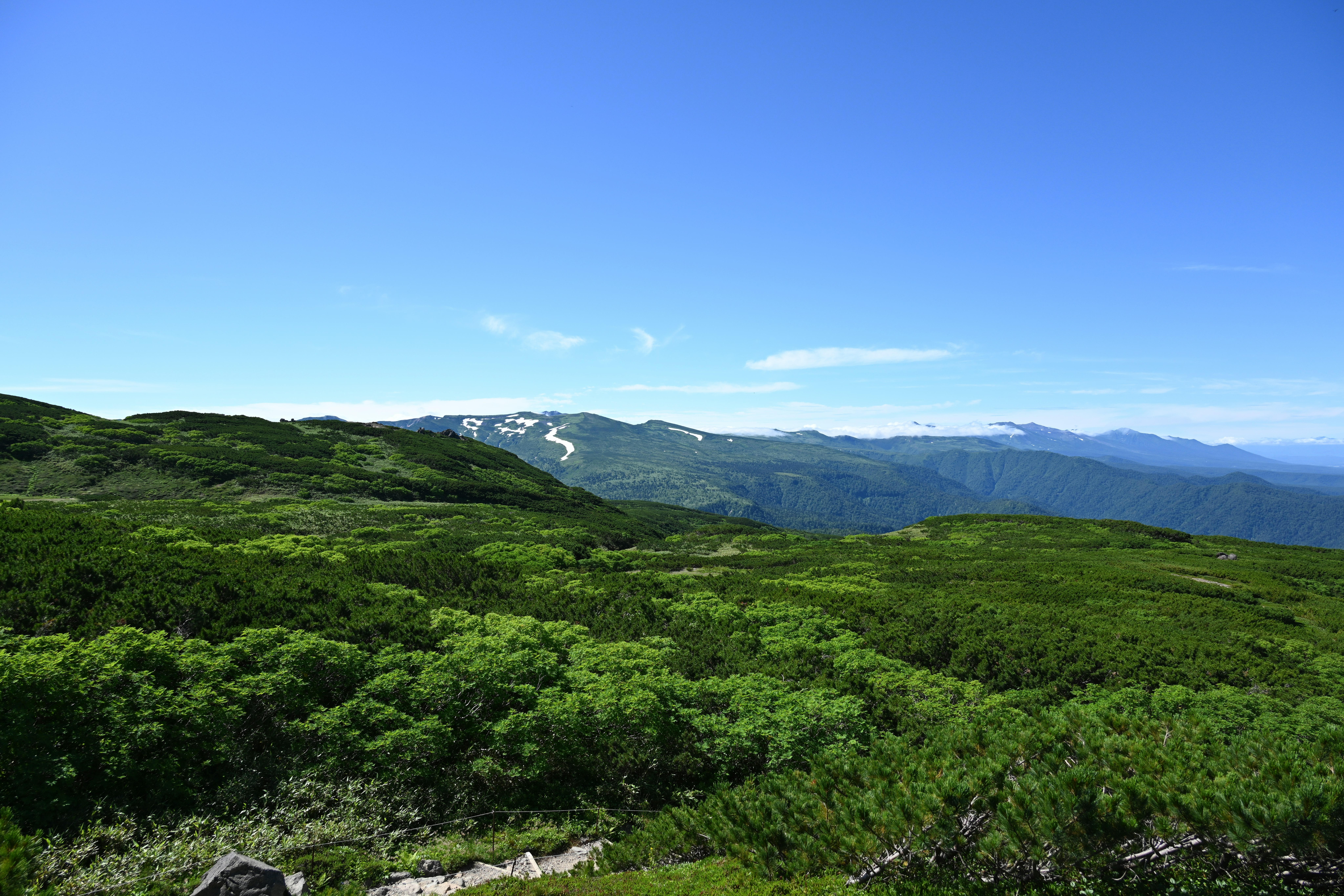Scenic view of green hills under a clear blue sky