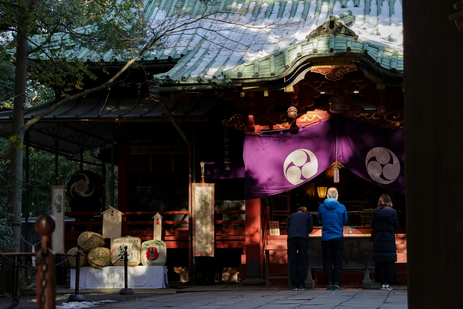 사람들이 보라색 천으로 장식된 신사 앞에서 기도하는 모습
