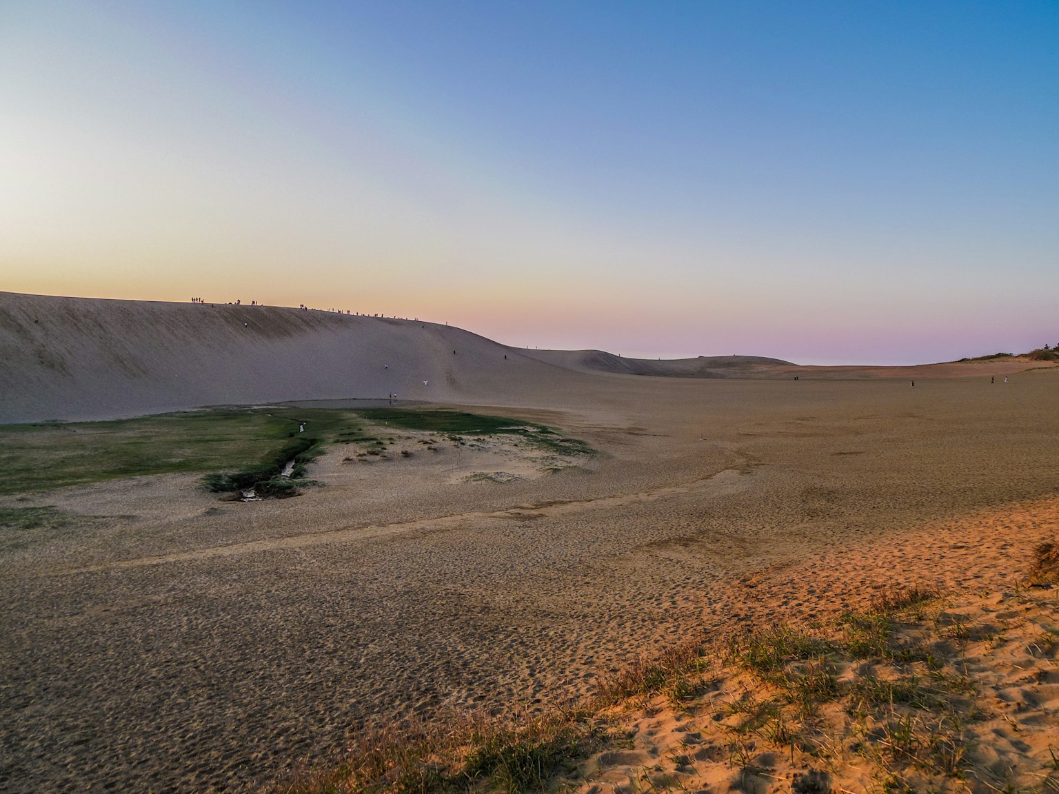 Weite Wüstenlandschaft mit ruhigem Sonnenuntergangshimmel