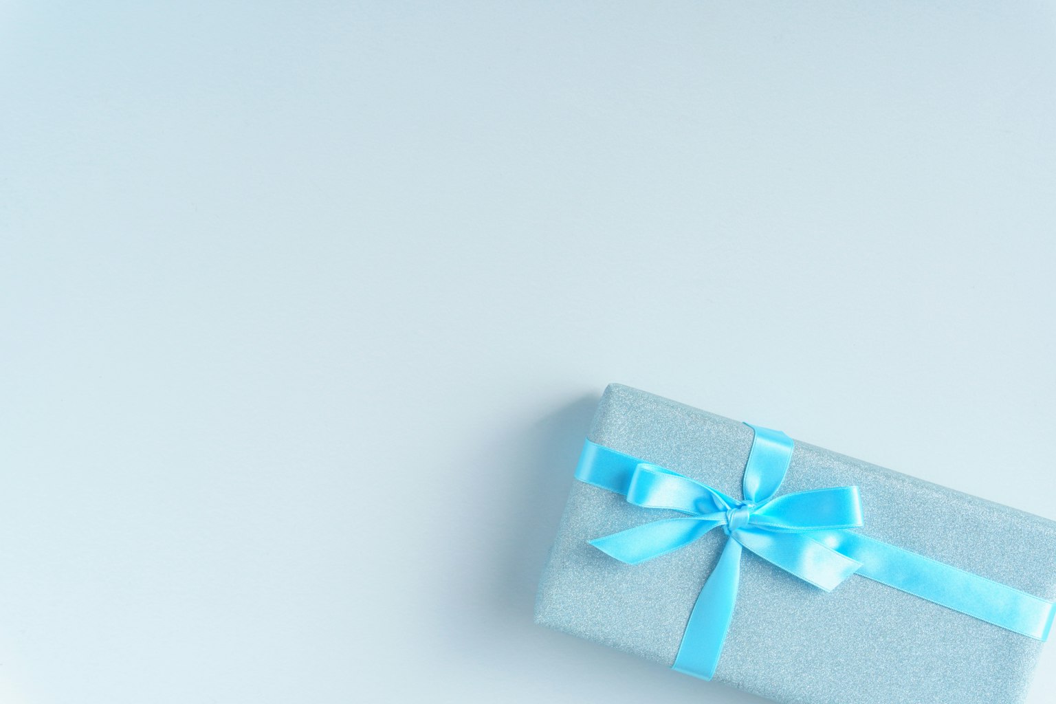 Eine silberne Geschenkbox mit einem blauen Band steht auf einem weißen Hintergrund