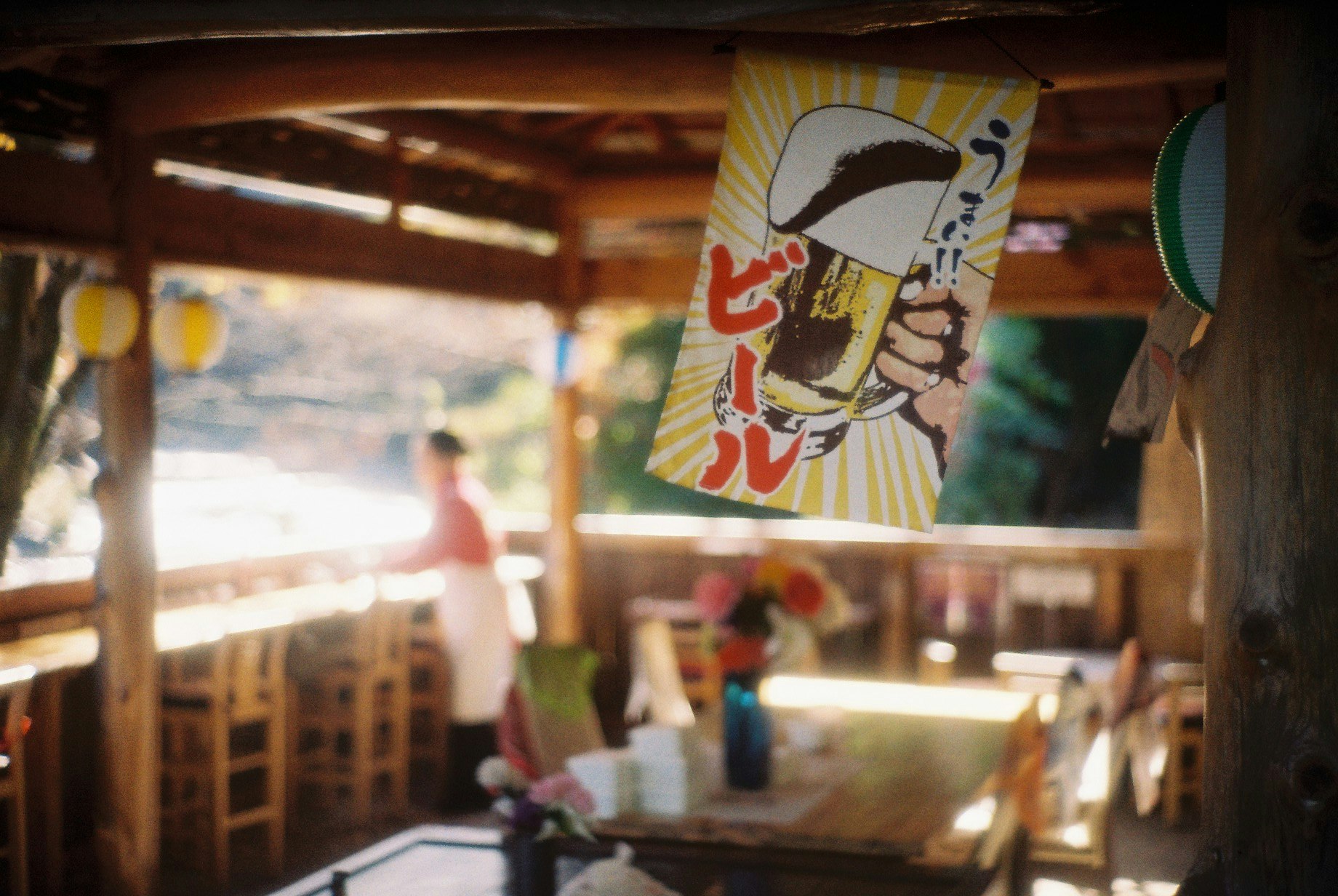 木の店内で掲げられたビール看板と奥の人影