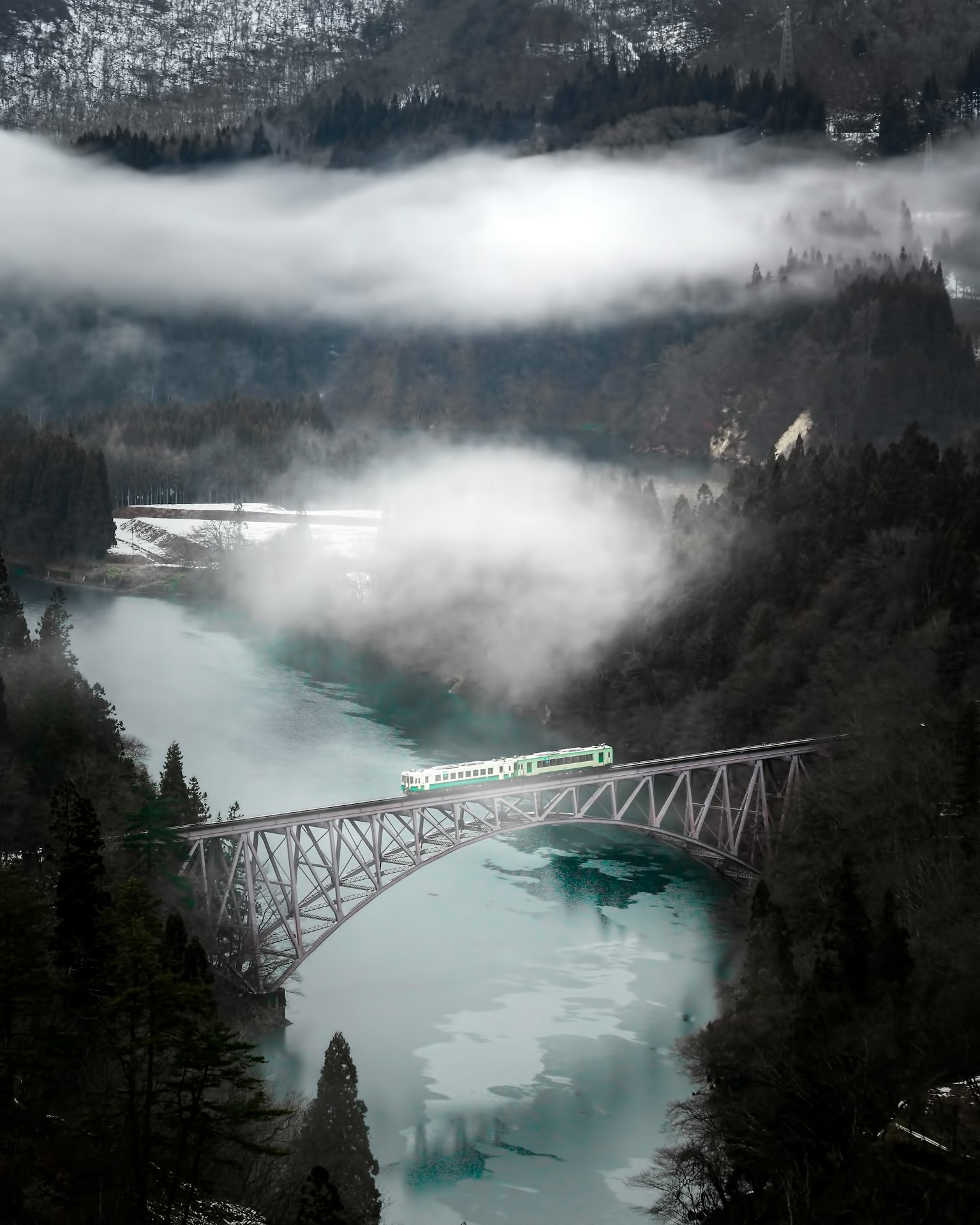 Une vue pittoresque d'un train traversant un pont de rivière enveloppé de brouillard
