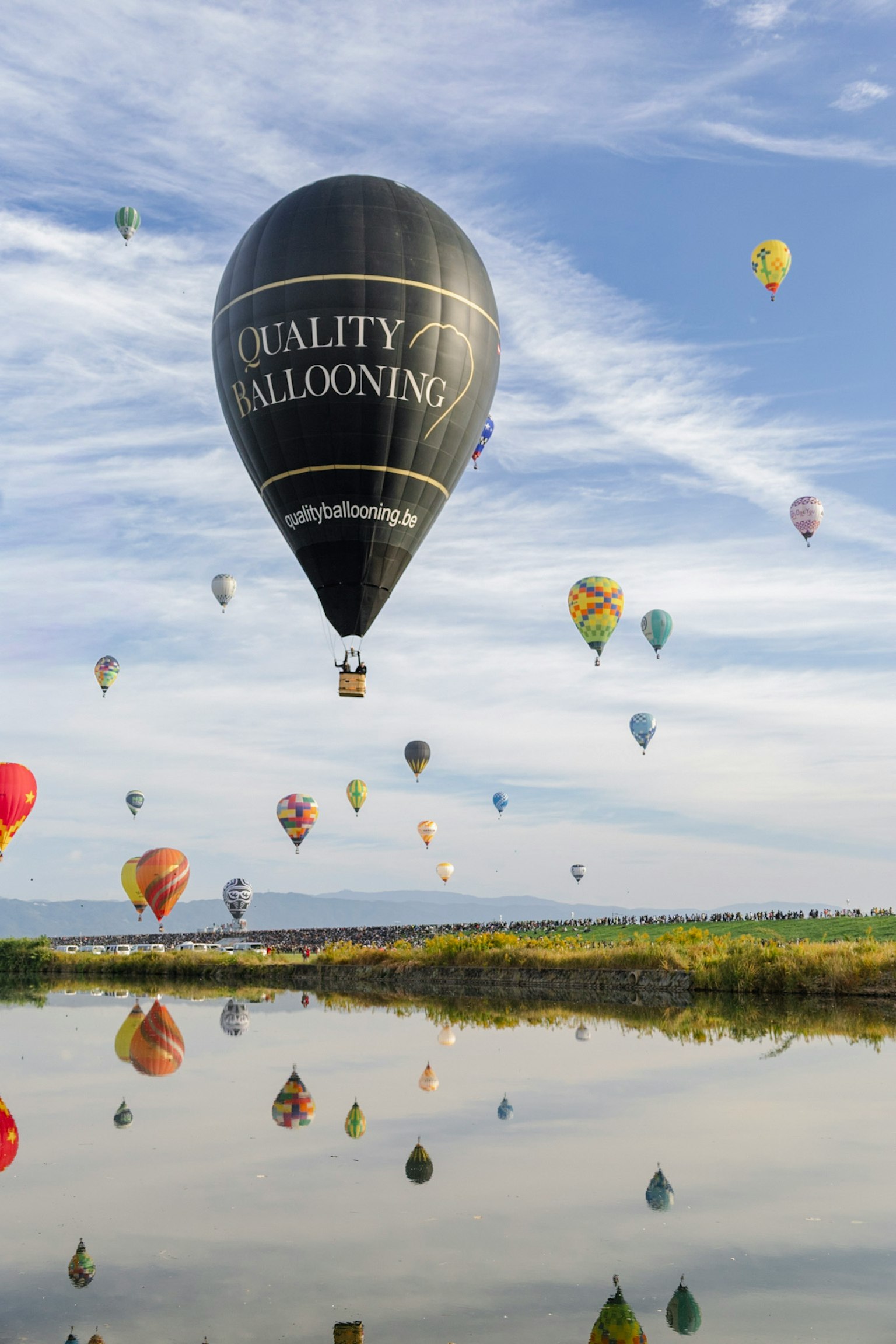 空に浮かぶカラフルな熱気球と静かな湖の風景