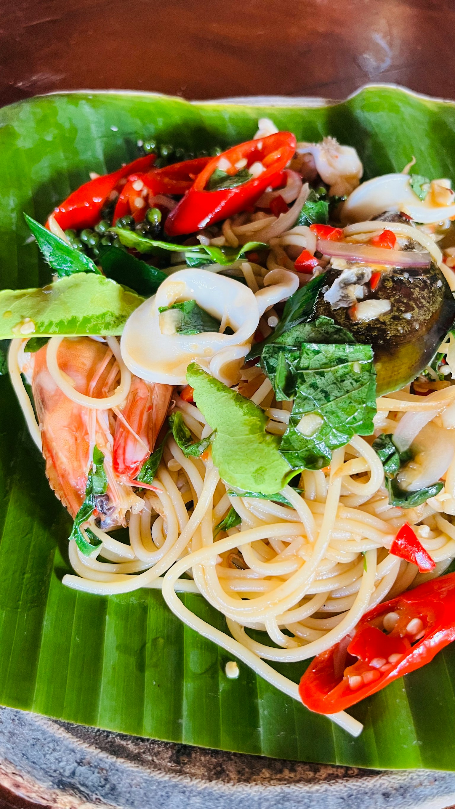 Espagueti de mariscos decorados con hierbas y chiles sobre una hoja de plátano
