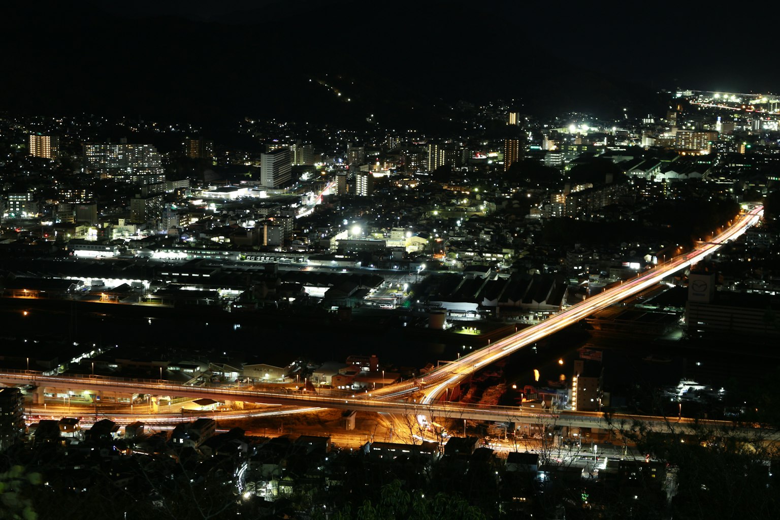 Paisaje urbano nocturno con autopista iluminada edificios y luces residenciales