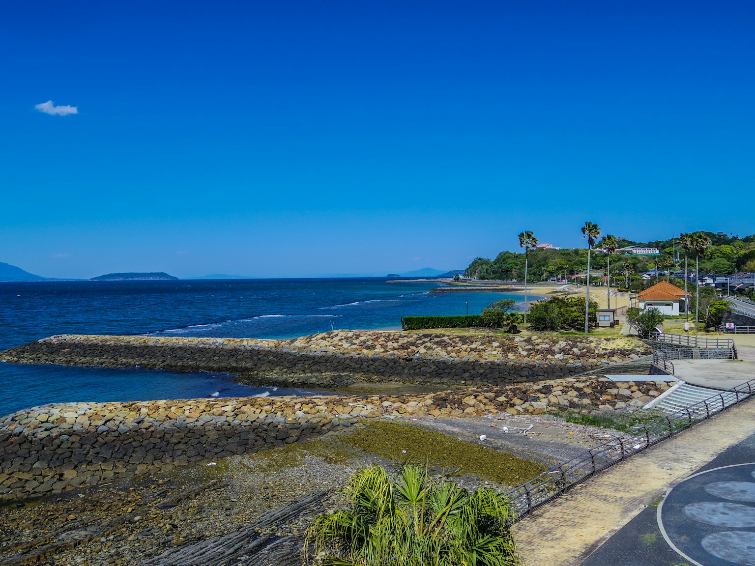 Paisaje costero con mar y cielo azules y una playa rocosa