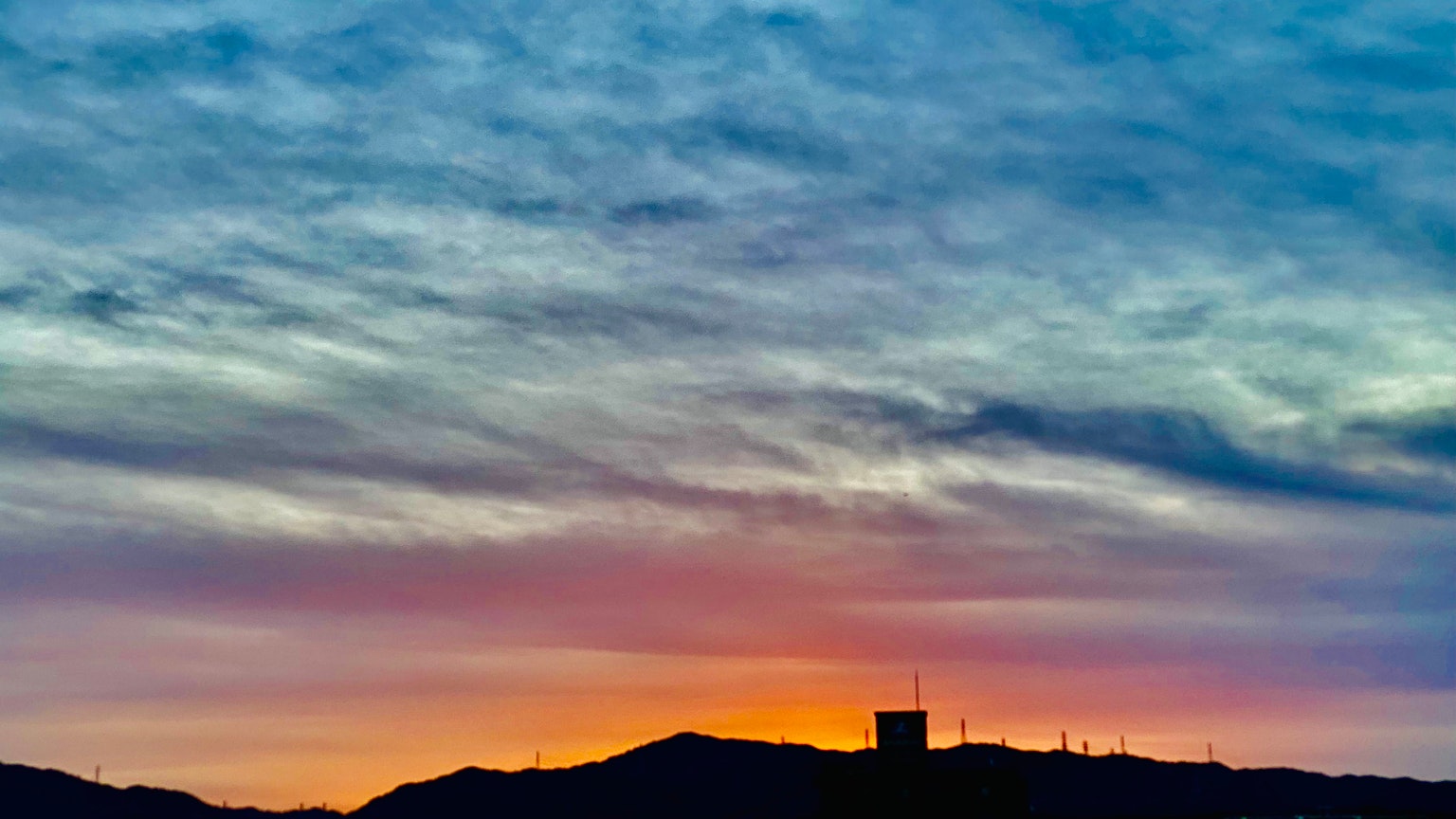 Schöner Sonnenuntergangshimmel mit silhouettierten Bergen