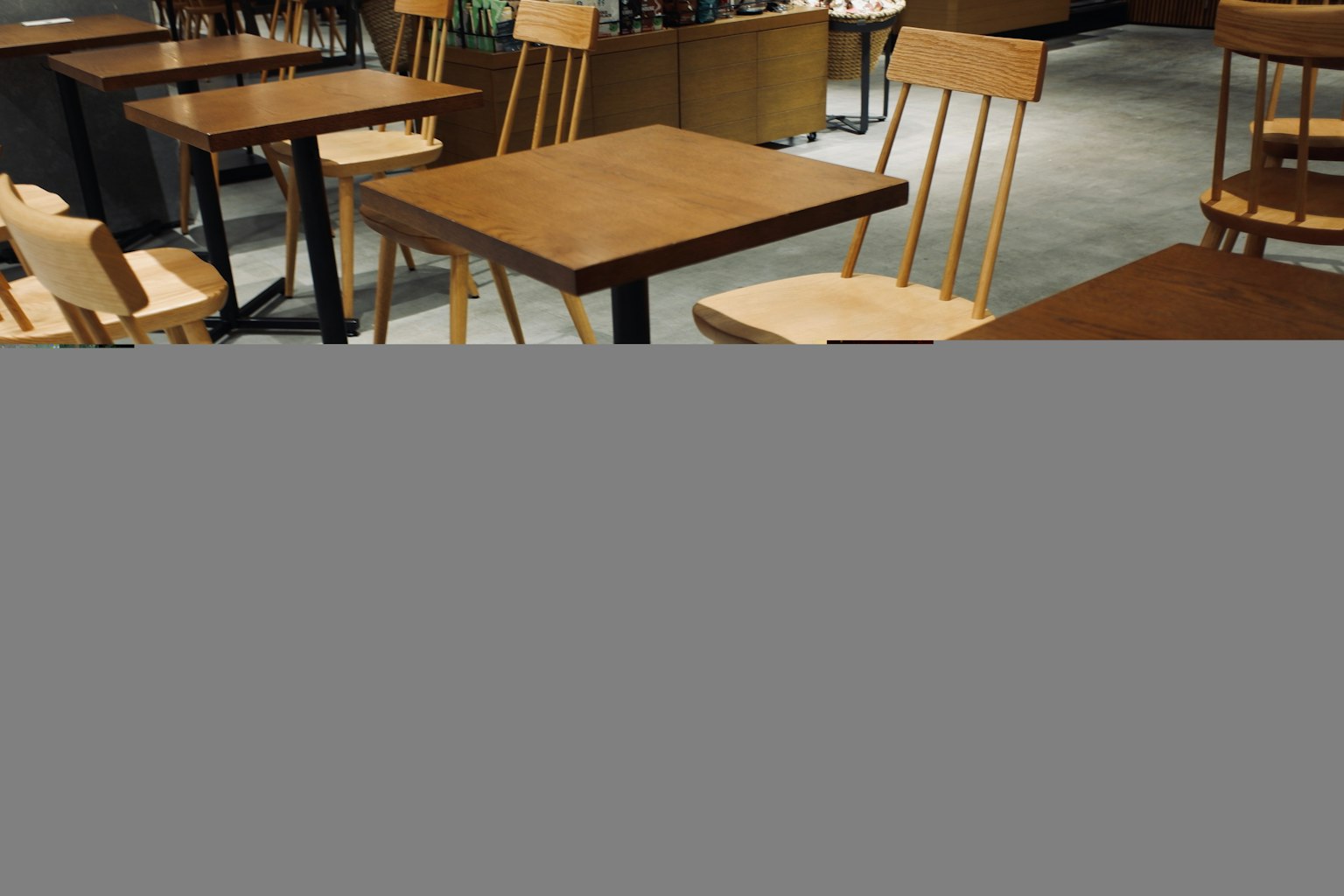 Interior de una cafetería con mesas y sillas de madera